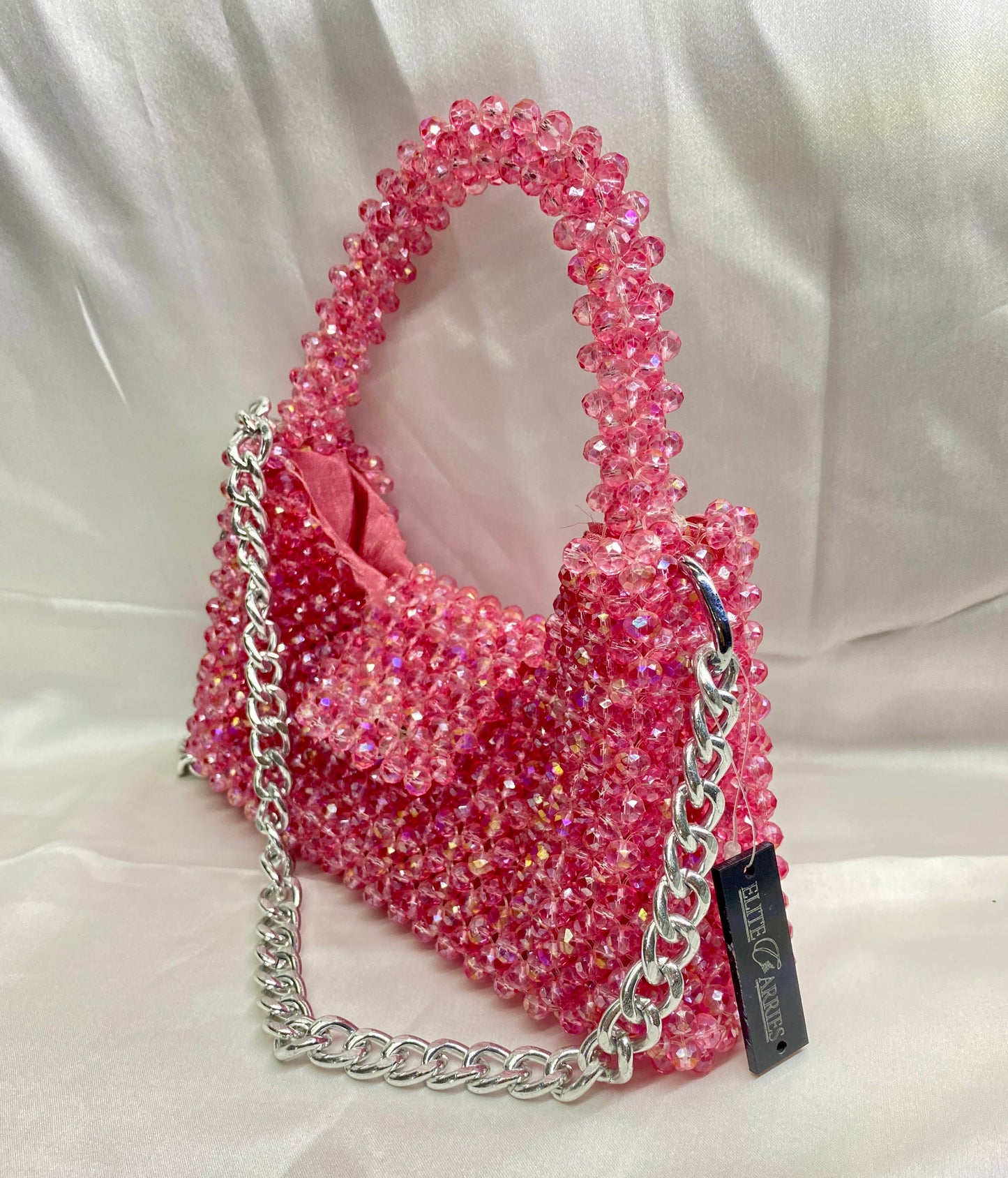 Pink beaded handbag with a chain detail on a white background