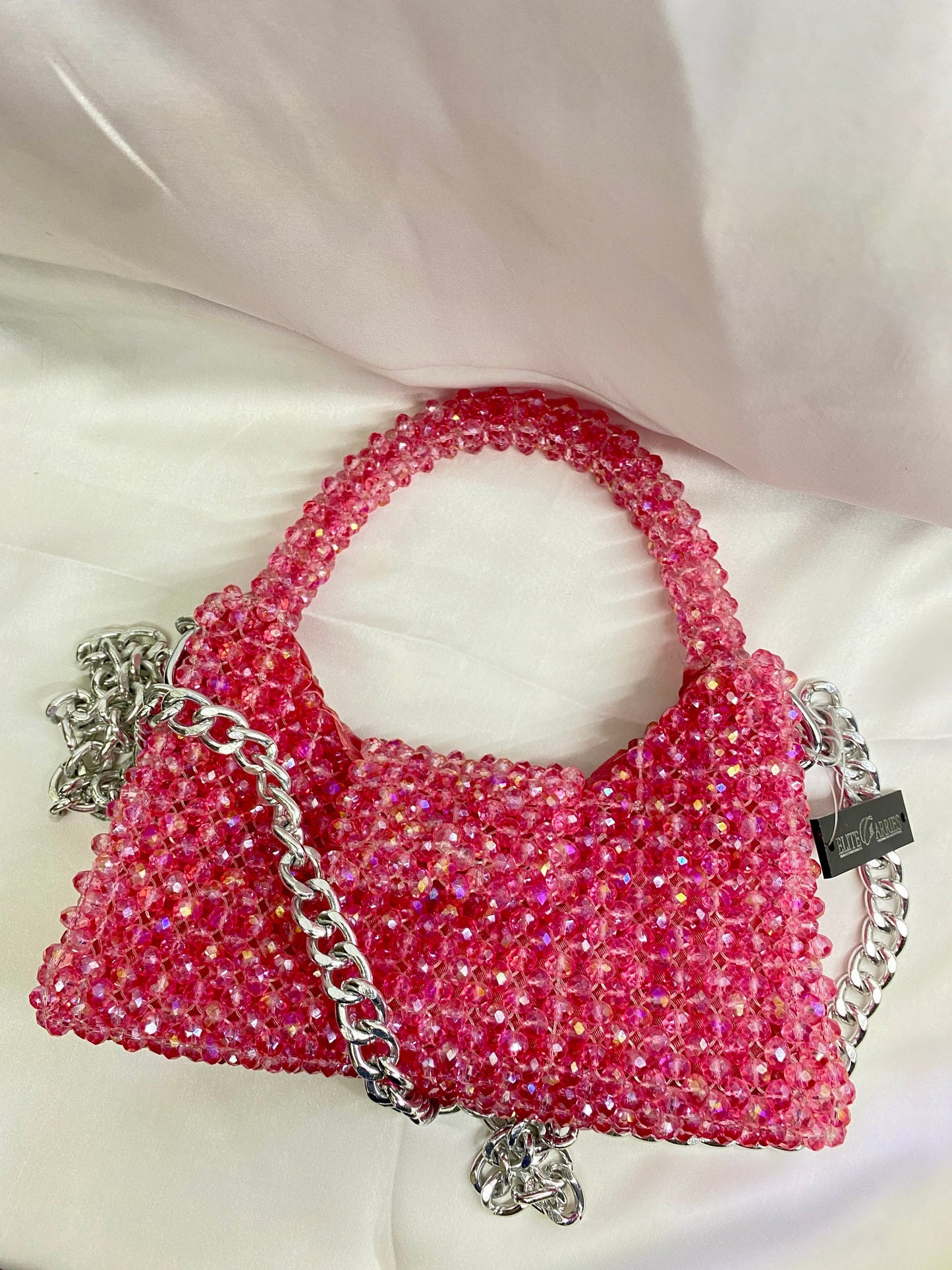 Pink beaded handbag with silver chain on a white background