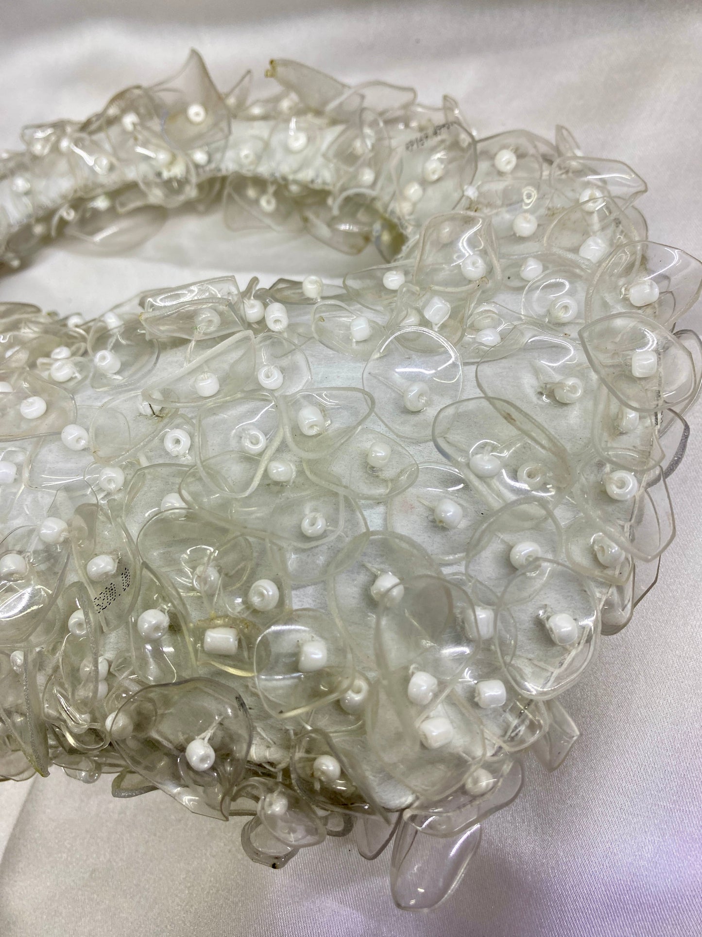 Close-up of a decorative headband with floral and pearl details on a white background