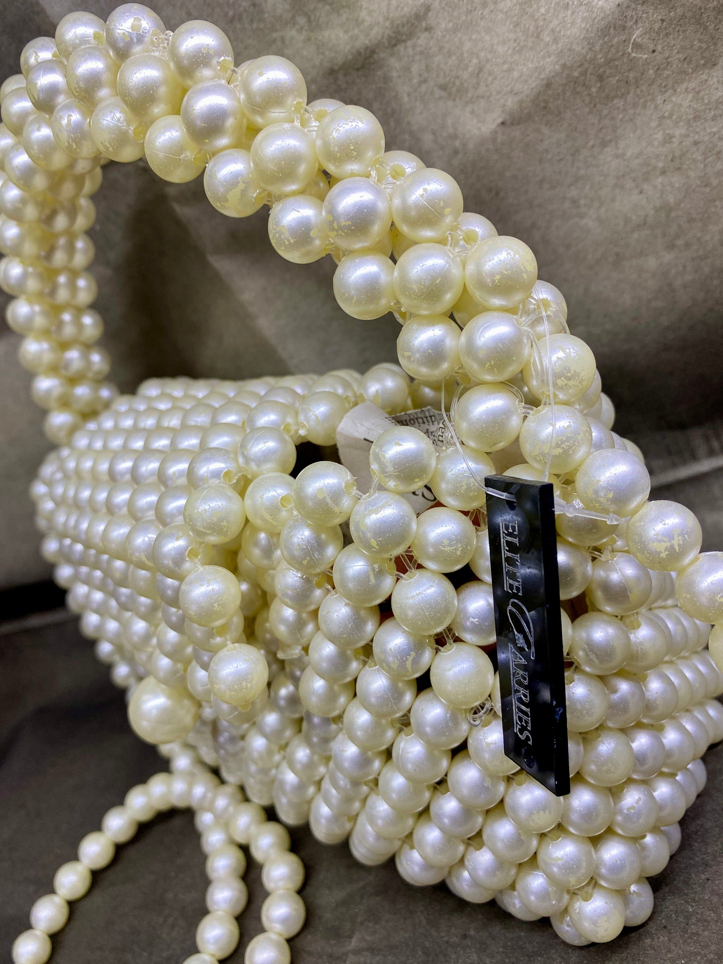 Pearl-handled handbag with a visible brand label on a neutral background
