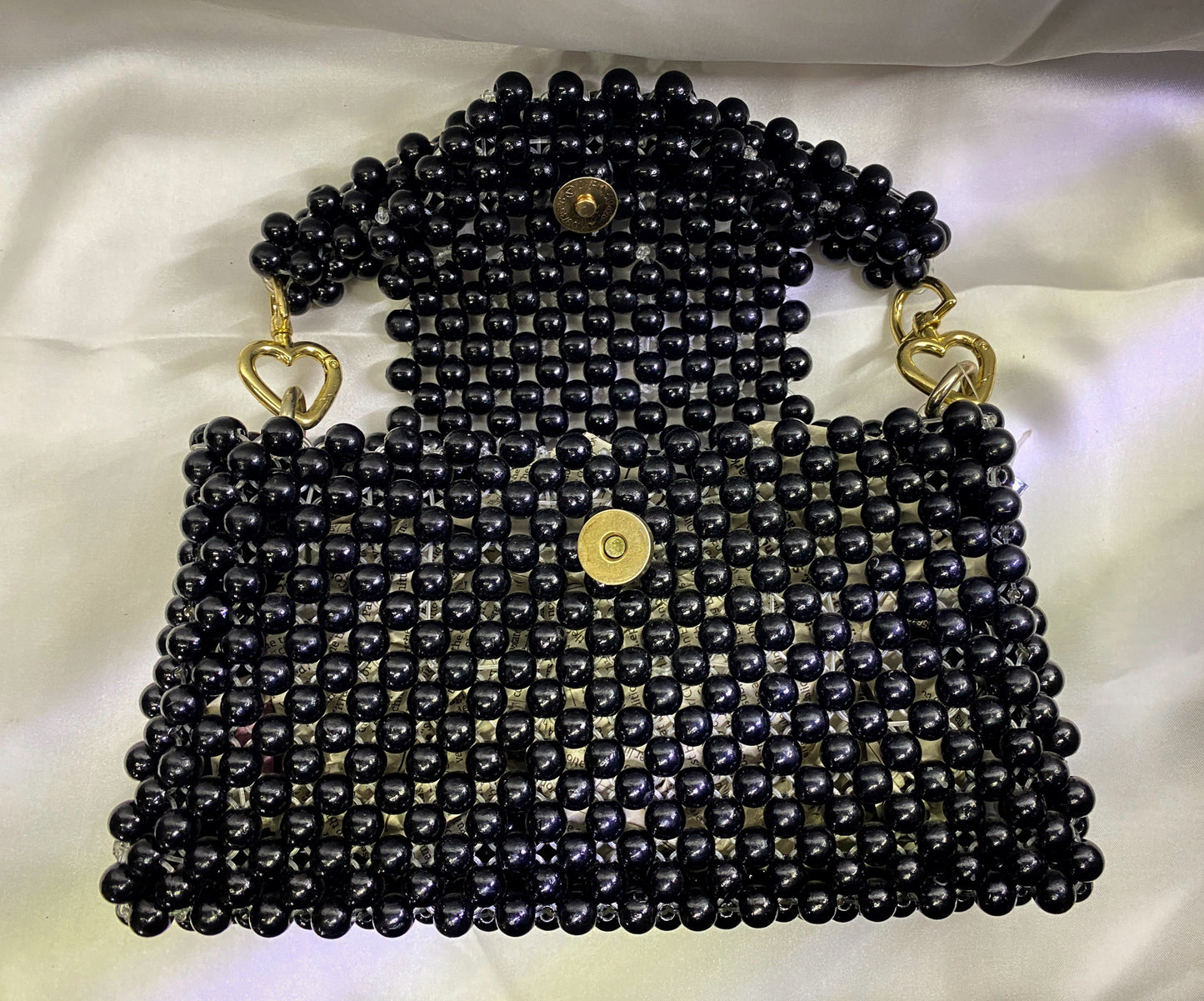 Black beaded handbag with gold accents on a white background
