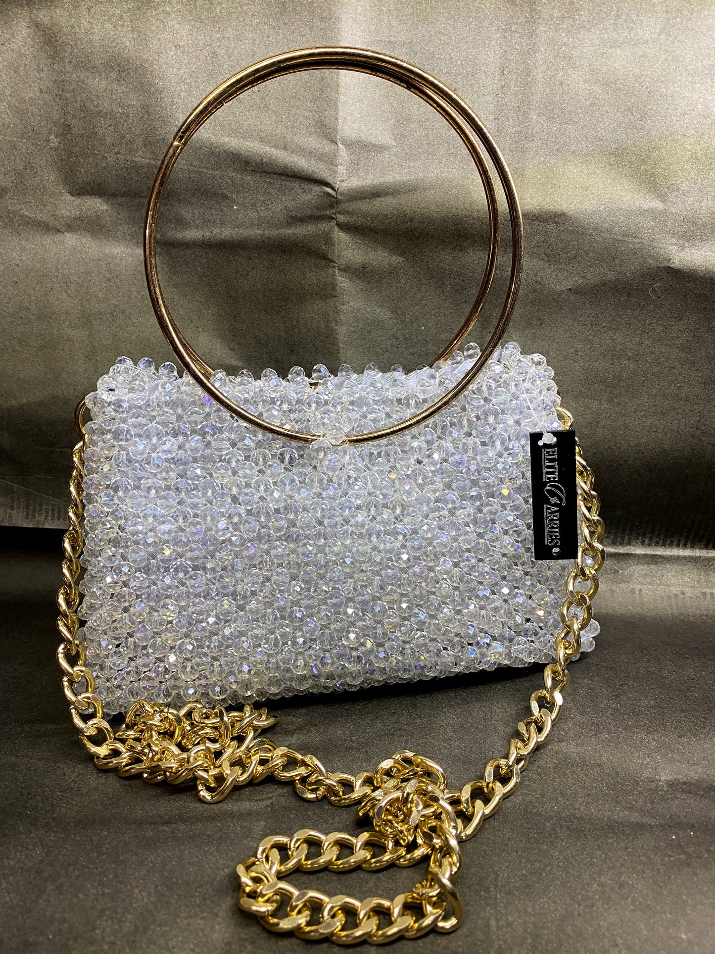 Silver beaded handbag with gold chain and handle on a gray background