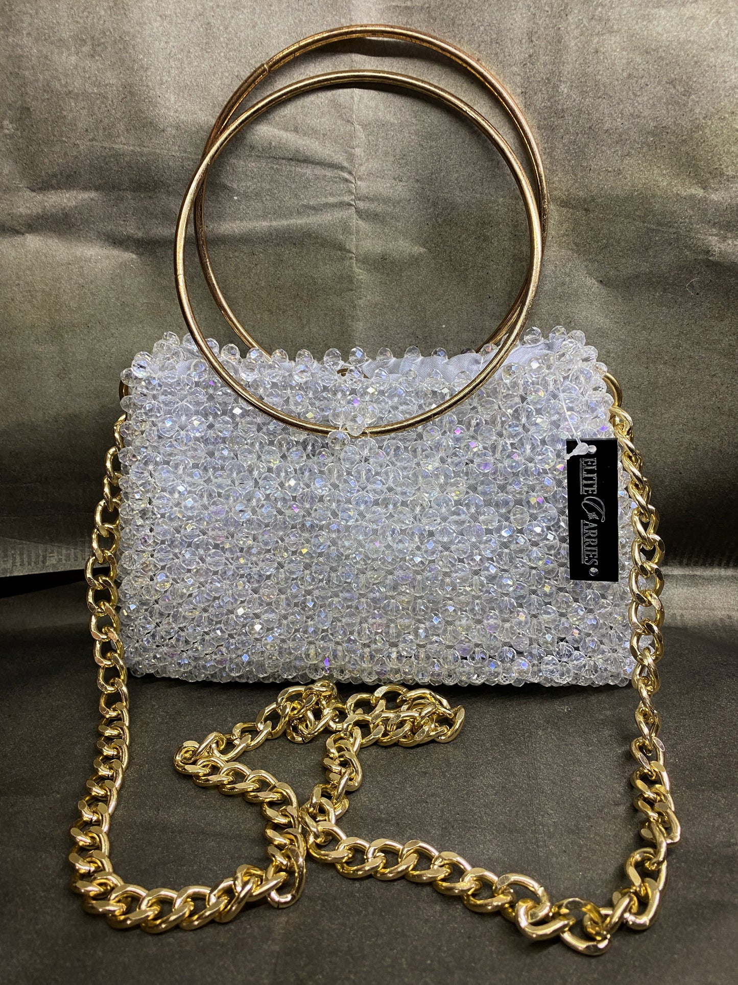 Silver beaded handbag with gold chain strap and circular handles on a gray background