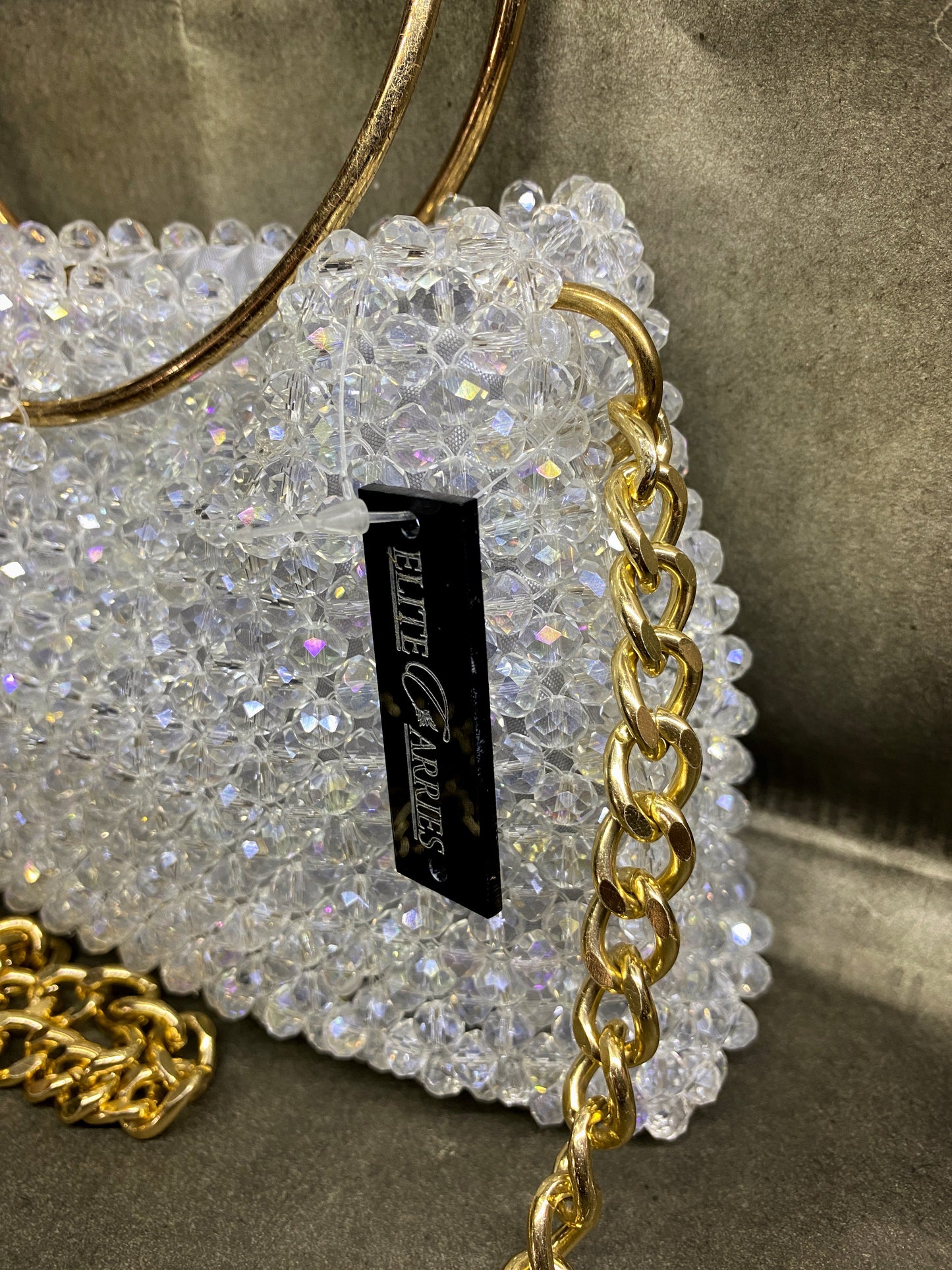 Sparkly handbag with gold chain detail and 'Elite Garret' label on a neutral background