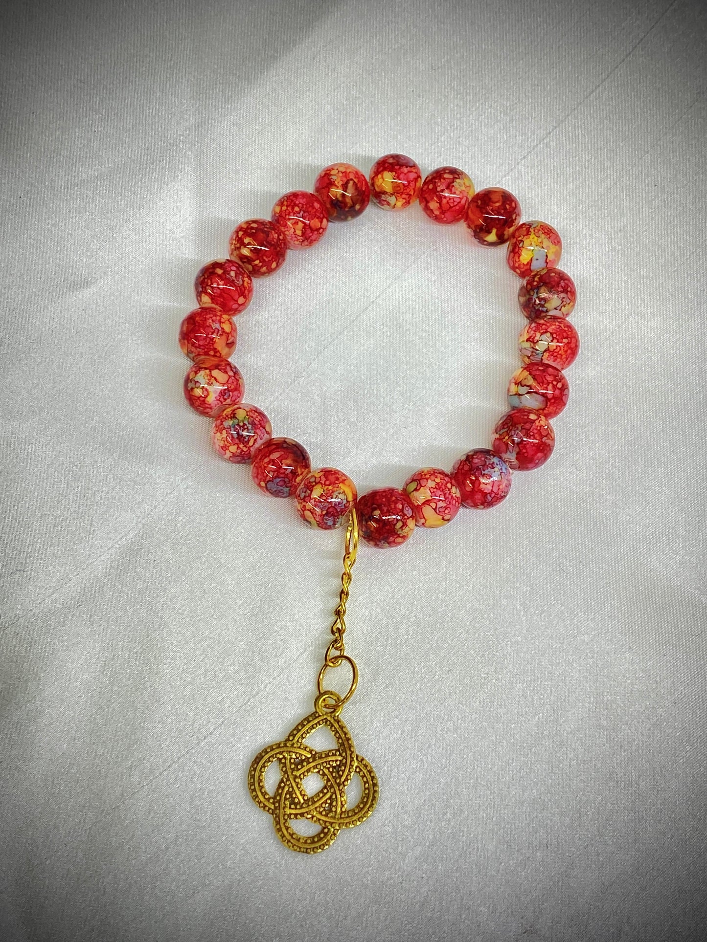 Beaded bracelet with a gold charm on a light gray background