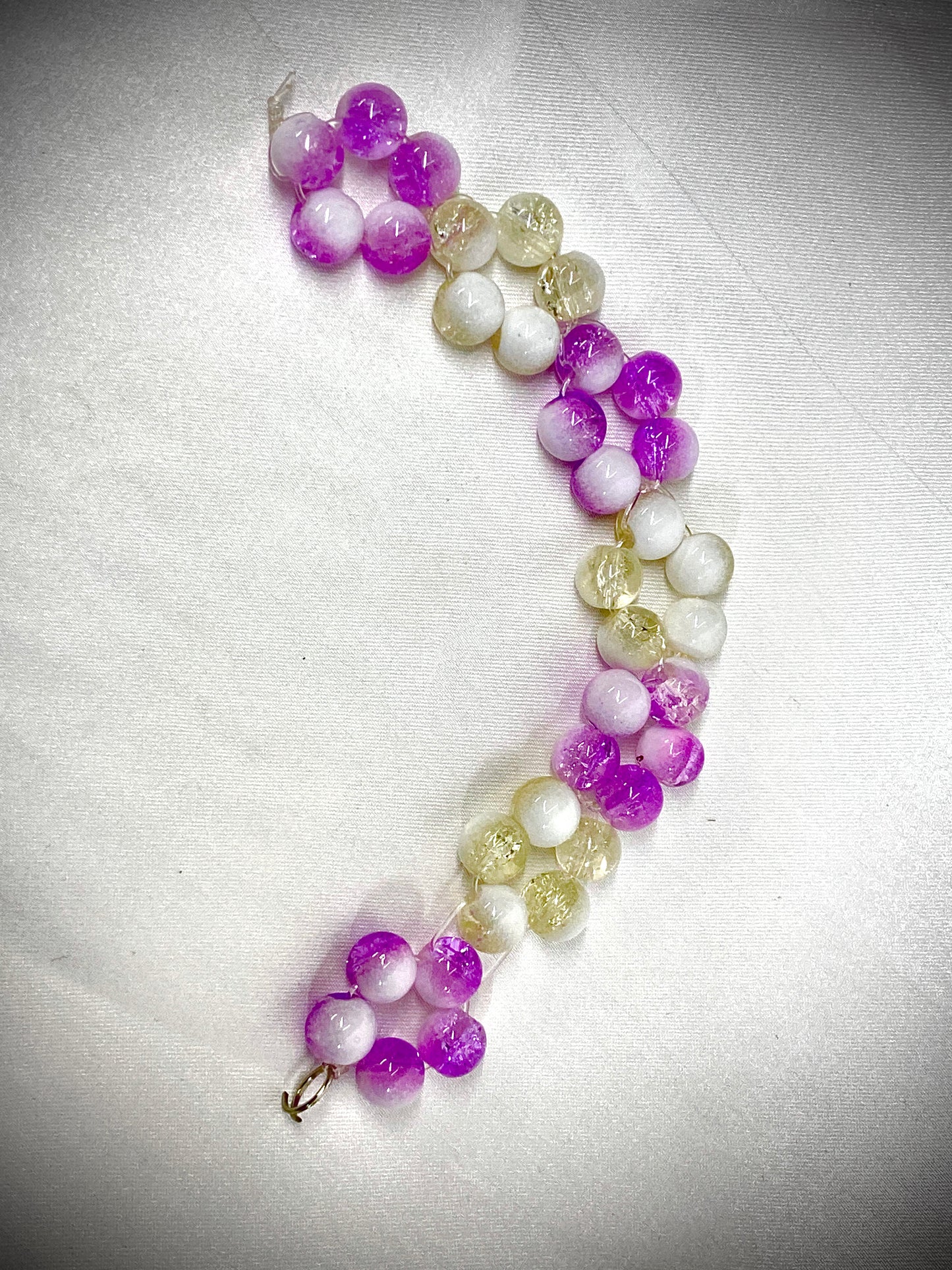 Beaded bracelet with purple and white beads on a light gray background