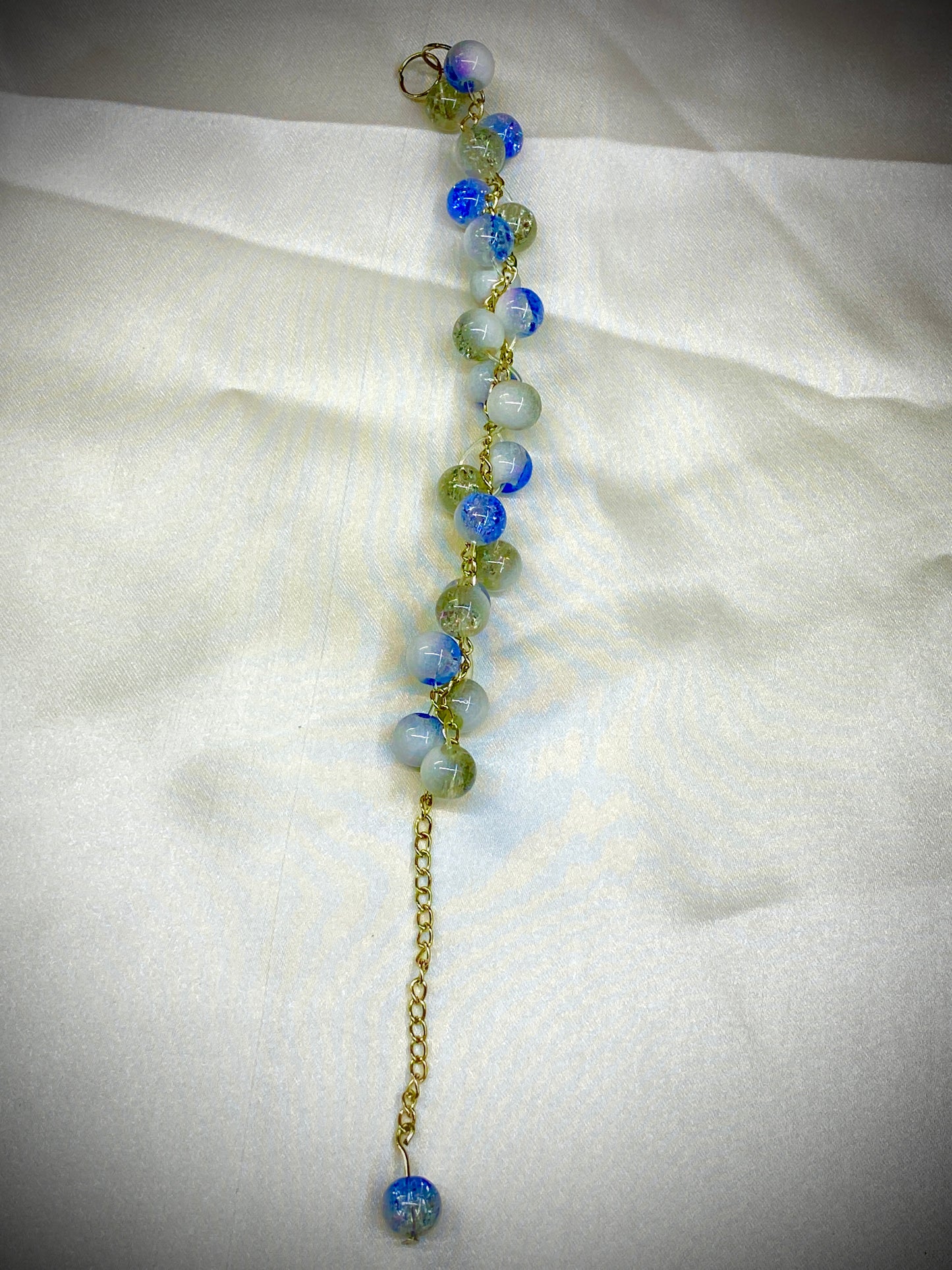 Beaded bracelet with blue and green beads on a white fabric background