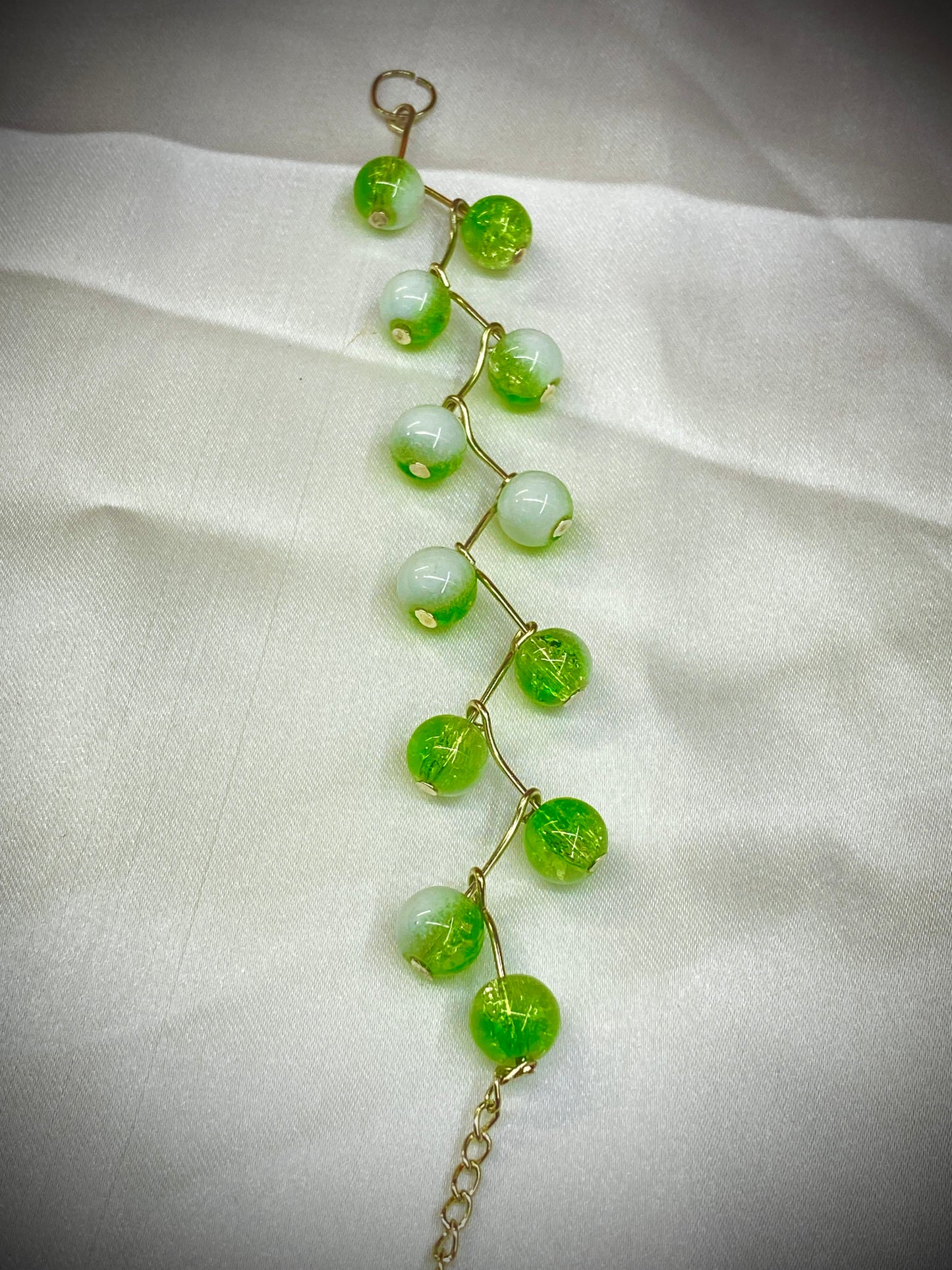 Green beaded bracelet on a white fabric background