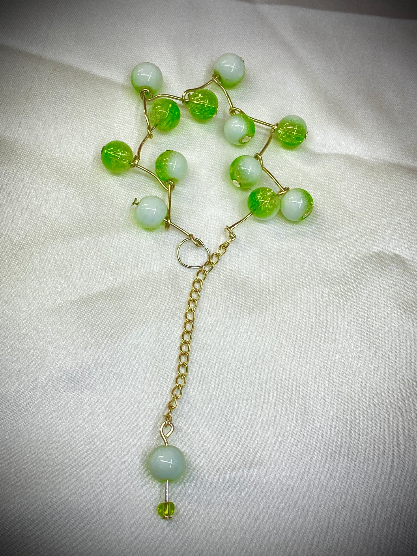 Necklace with green and white beads on a light fabric background