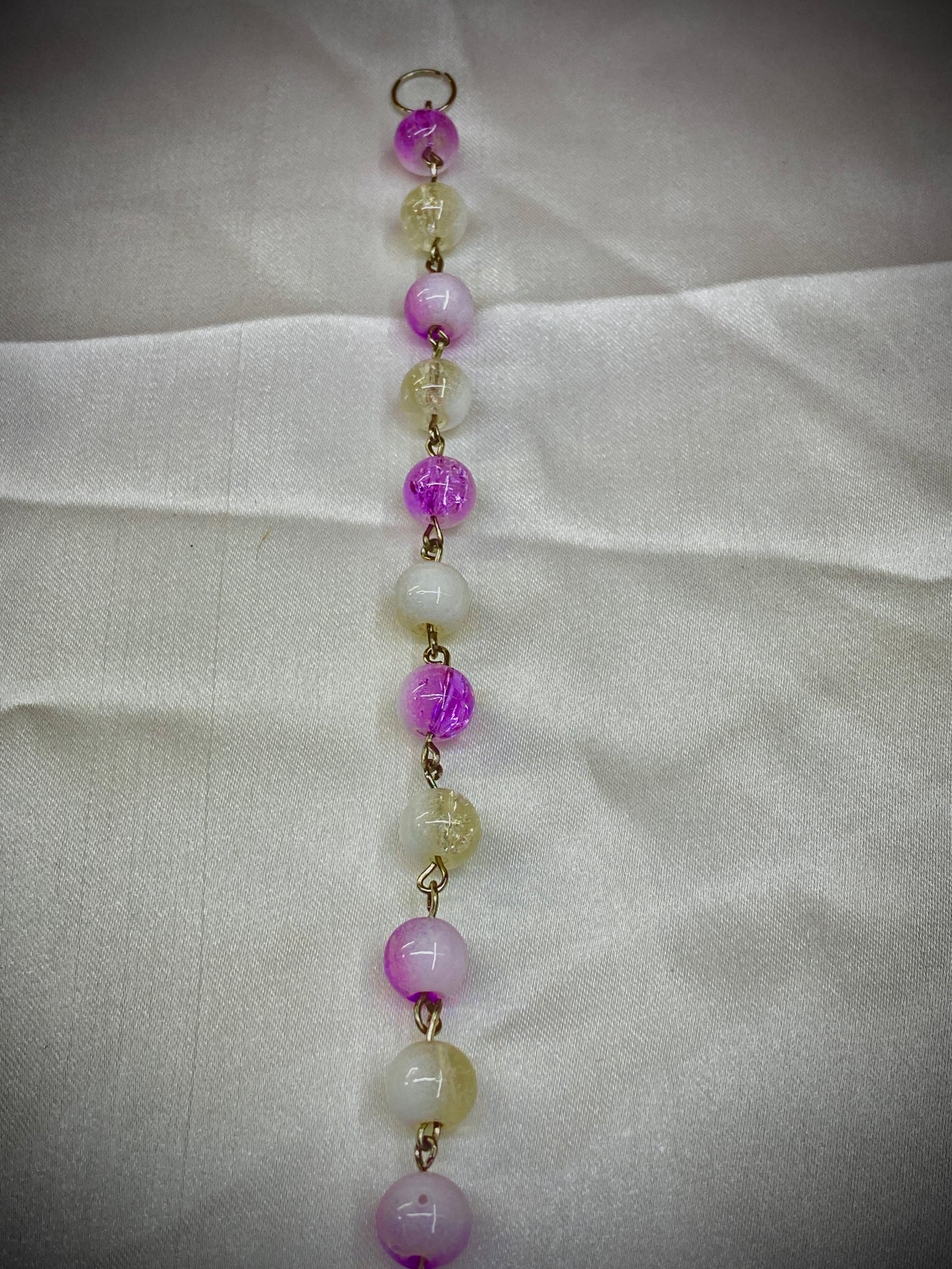 Beaded necklace with pink and yellow beads on a light fabric background