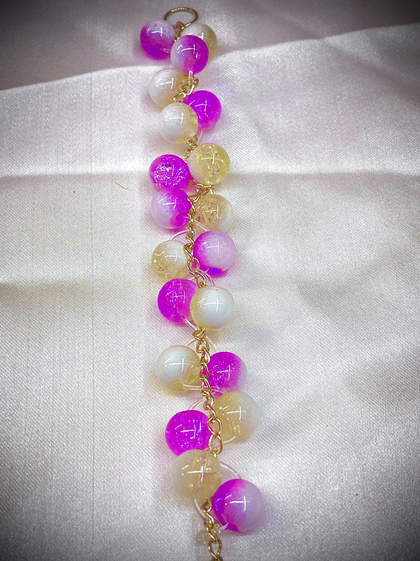 Bracelet with purple and yellow beads on a white fabric background