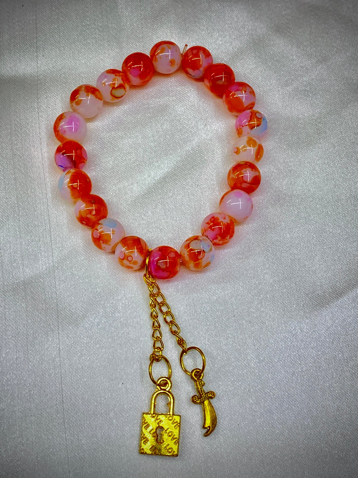 Beaded bracelet with a gold lock charm on a light gray background