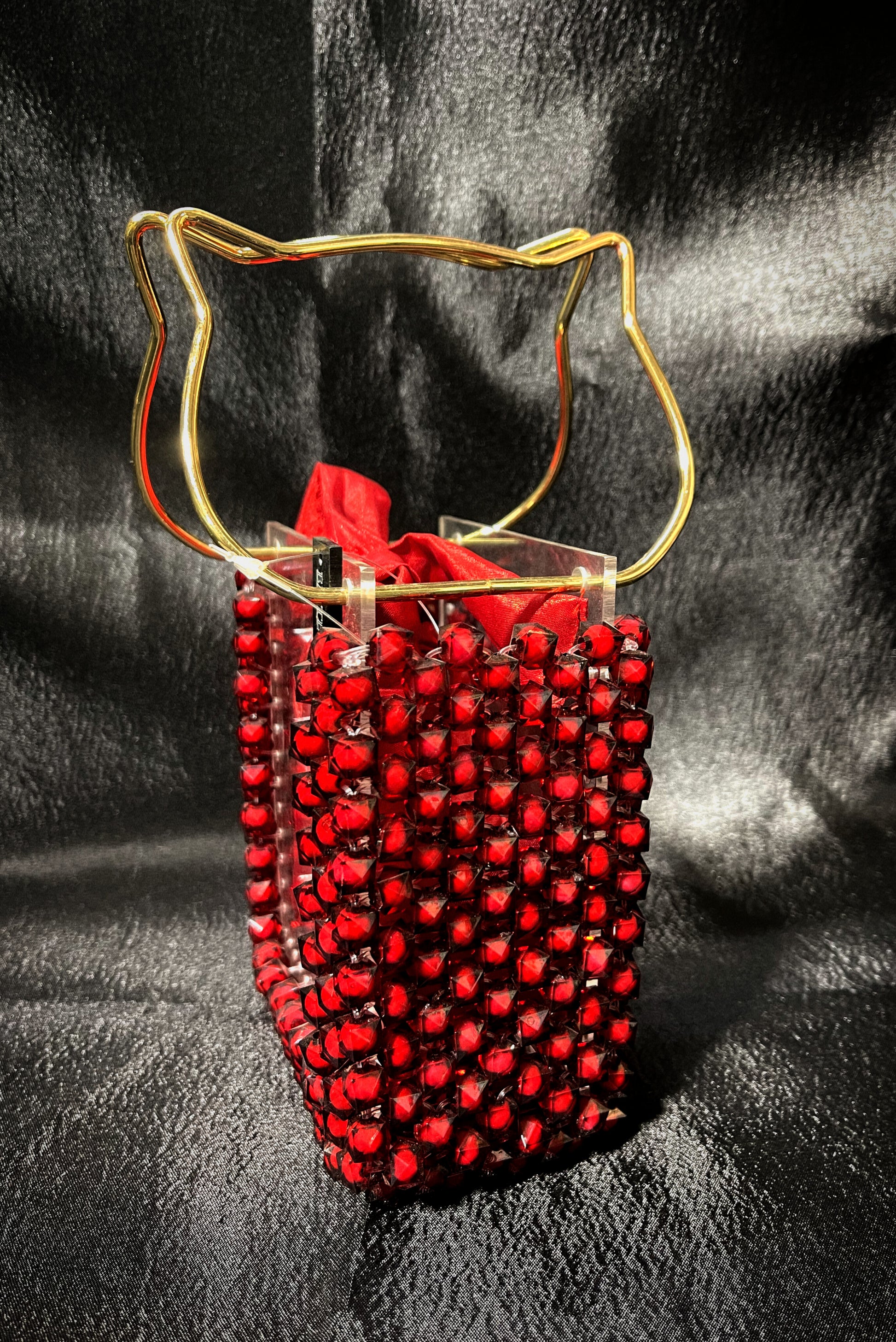 A vibrant red handbag with glass detailing, perfect for a bold and glamorous statement