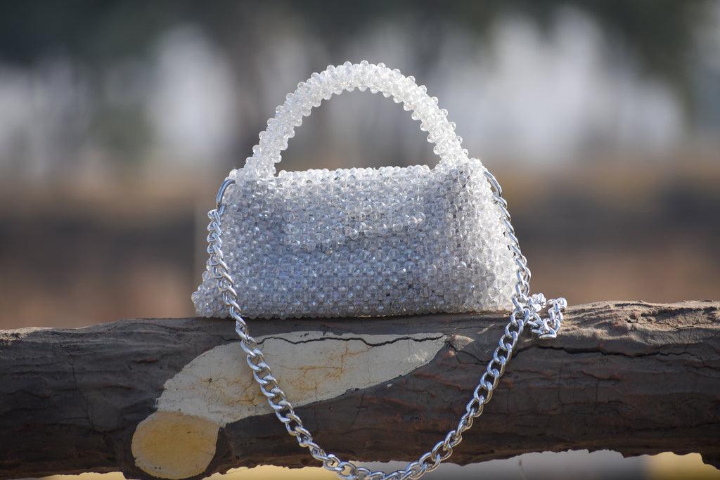 Silver beaded handbag with chain strap on a wooden branch