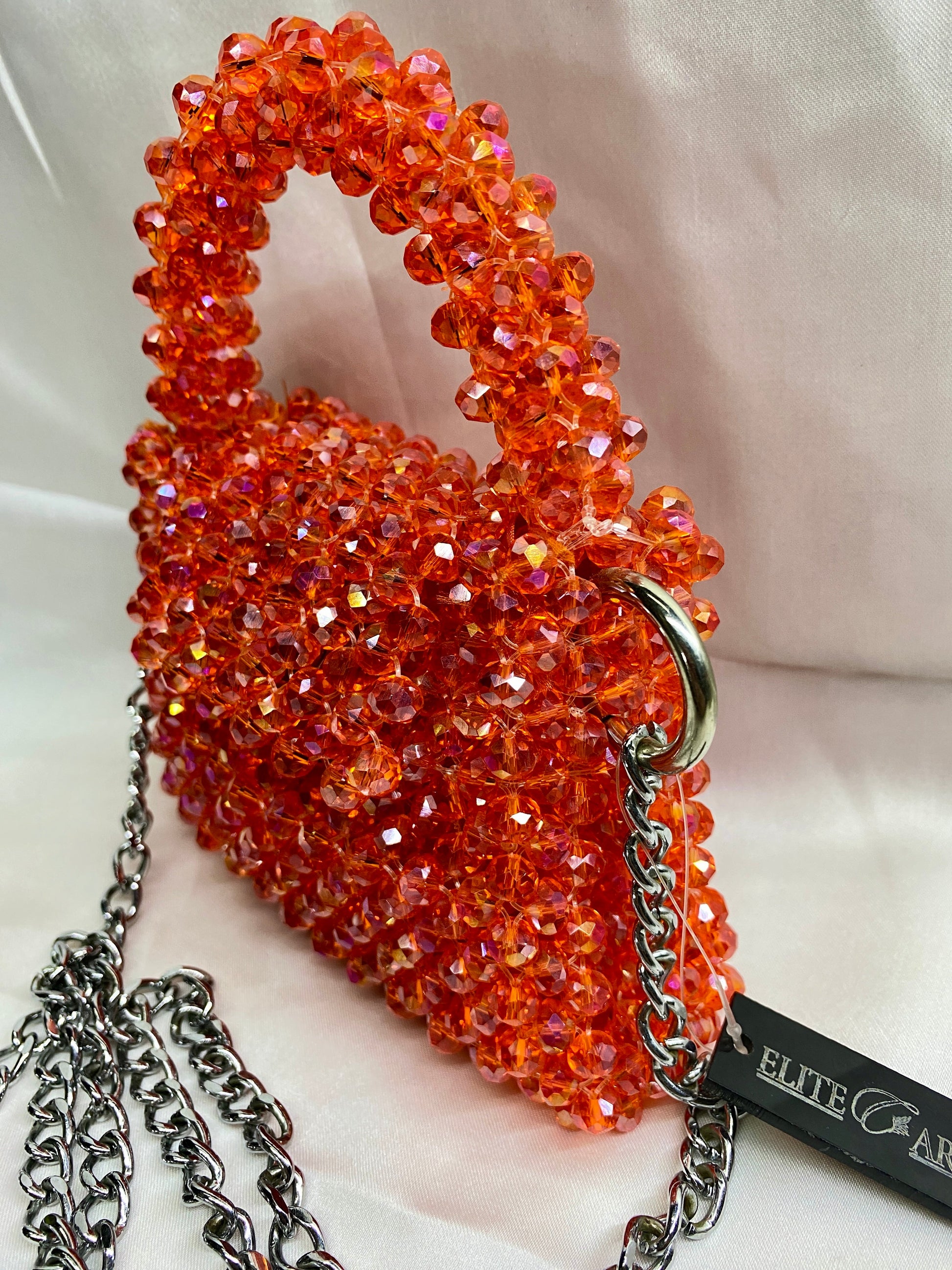 Orange beaded handbag with chain strap on a white background