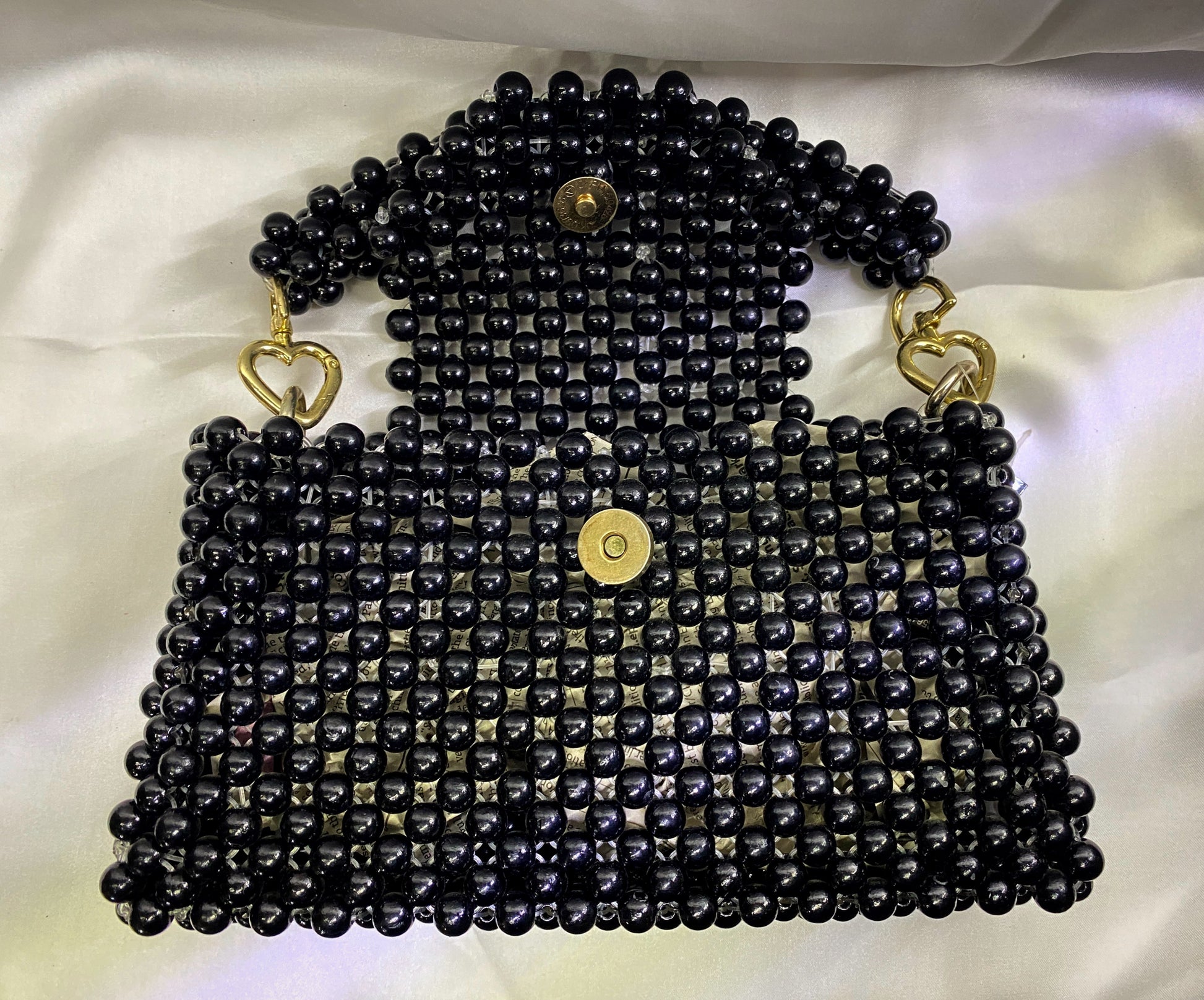 Black beaded handbag with gold accents on a white background