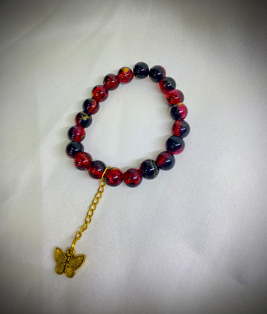 Beaded bracelet with a gold chain and butterfly charm on a white background