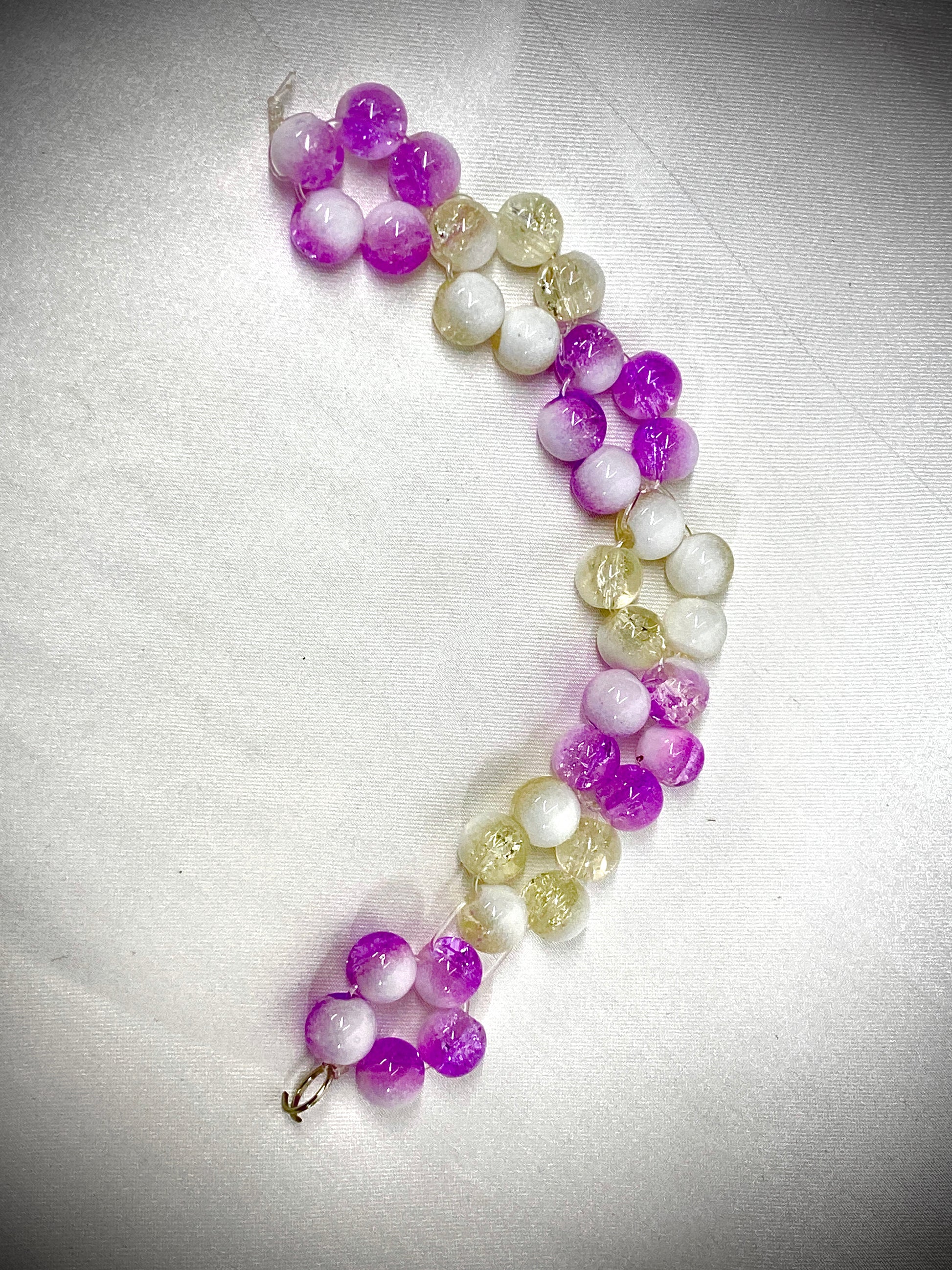 Beaded bracelet with purple and white beads on a light gray background