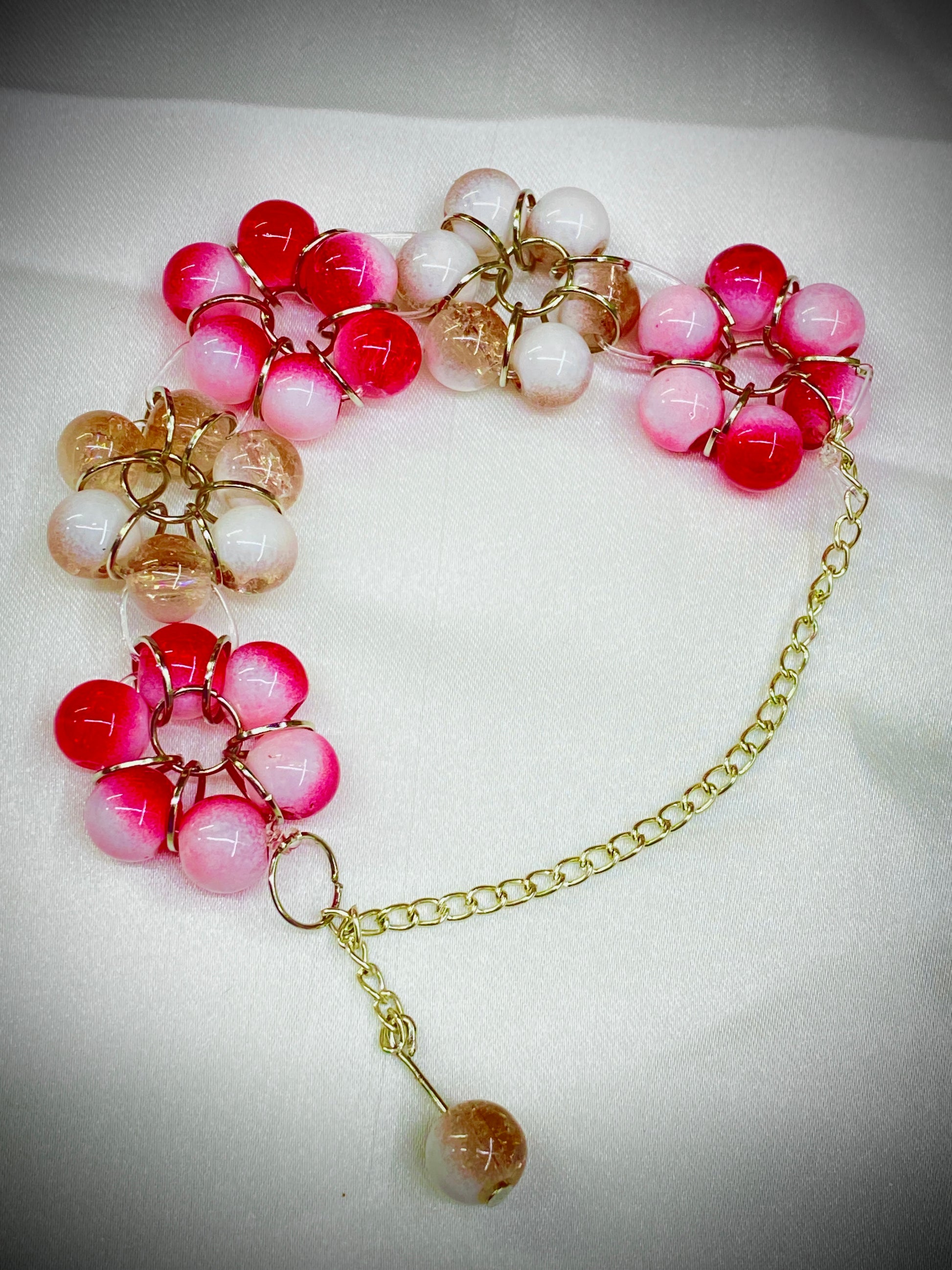 Bracelet with pink and white beads on a gold chain against a white background