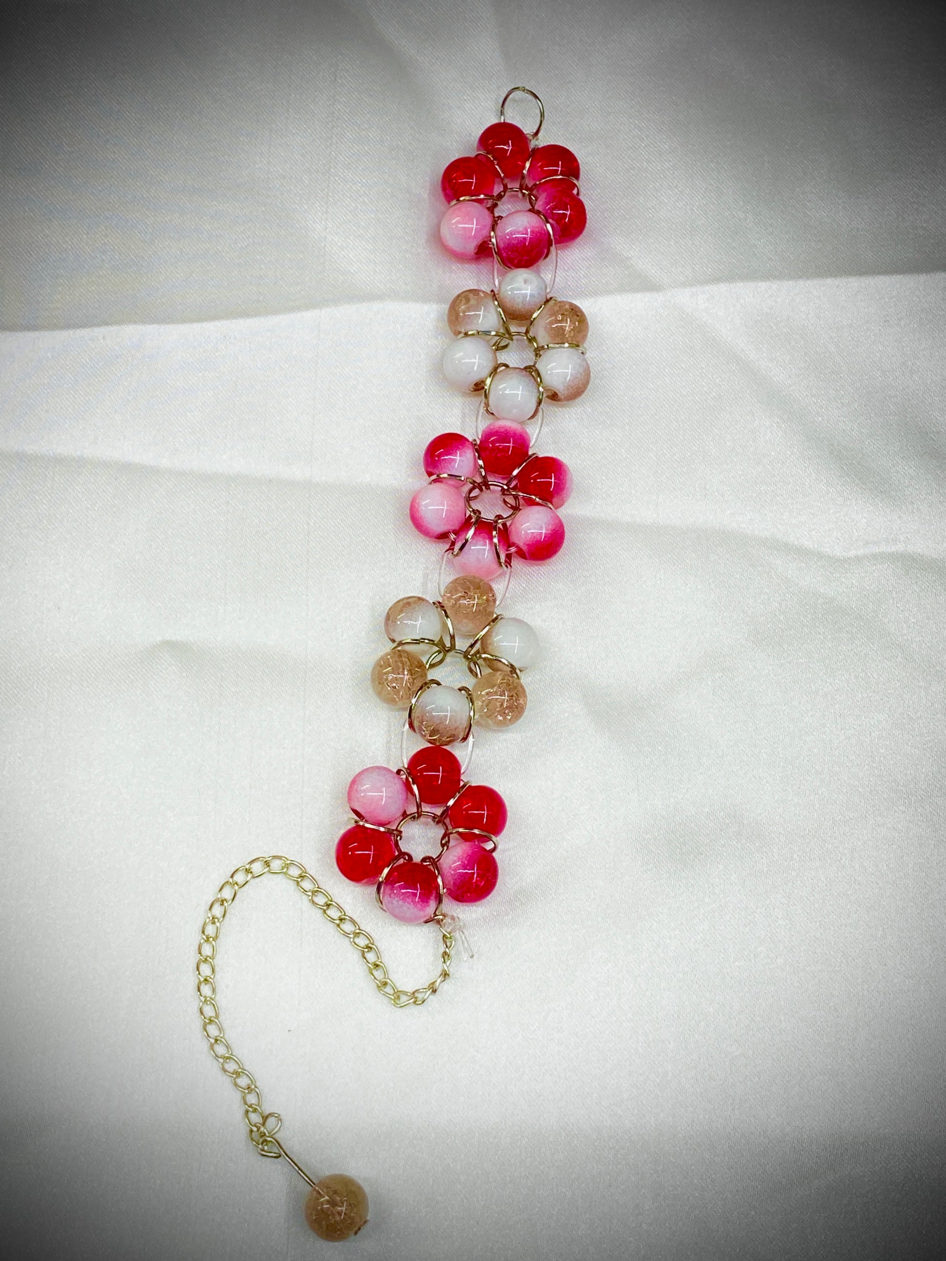 Beaded necklace with pink, red, and white beads on a white fabric background