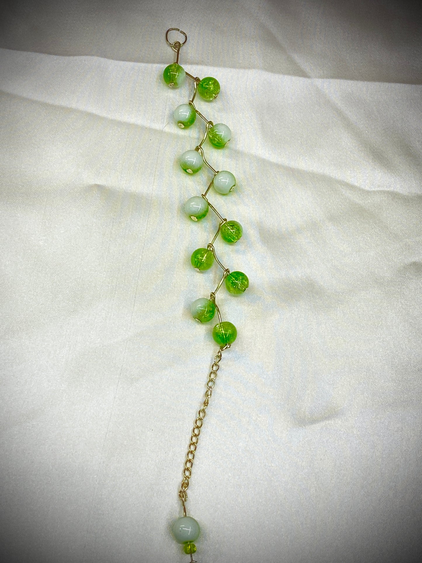 Green beaded necklace on a white fabric background