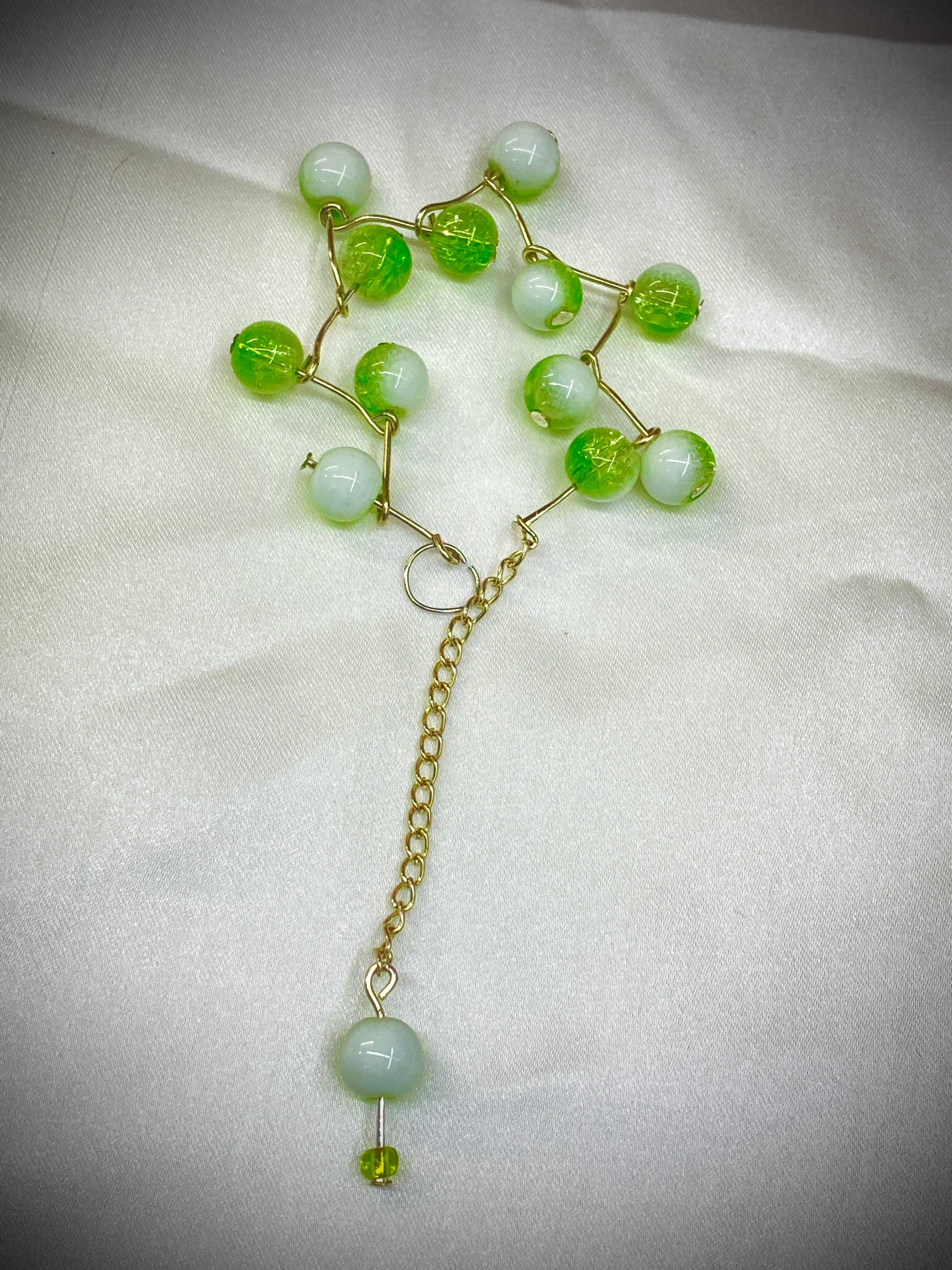 Necklace with green and white beads on a light fabric background