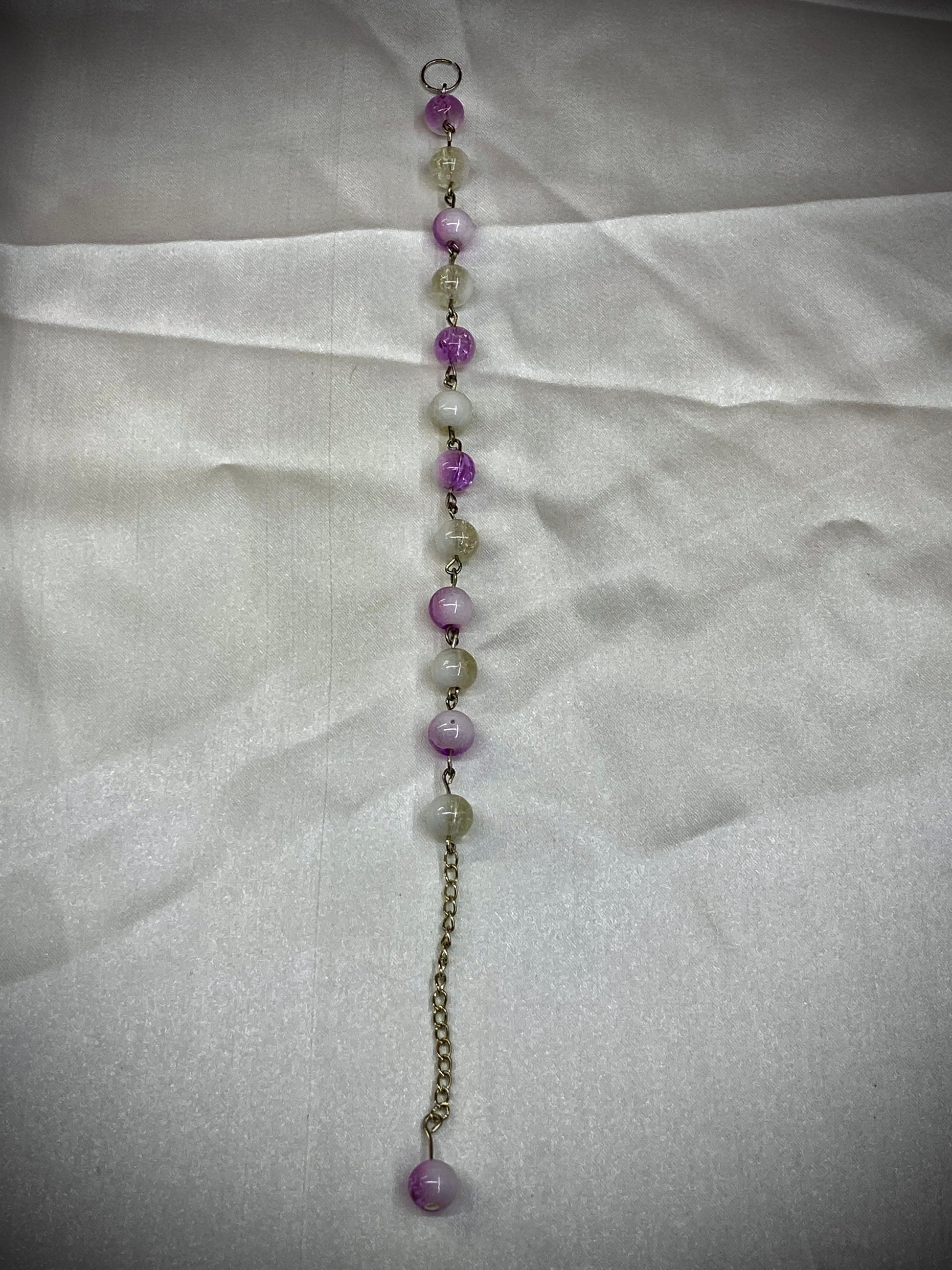 Beaded necklace with purple and clear beads on a white fabric background