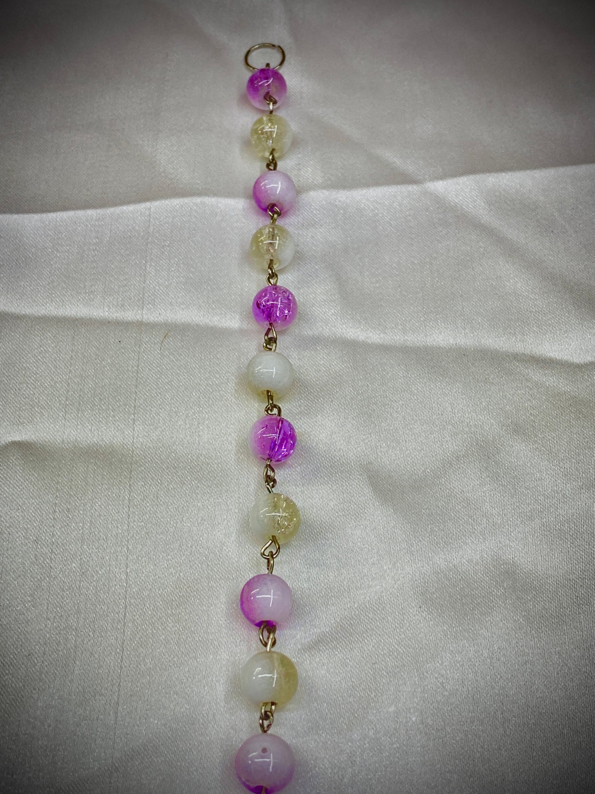 Beaded necklace with pink and yellow beads on a light fabric background
