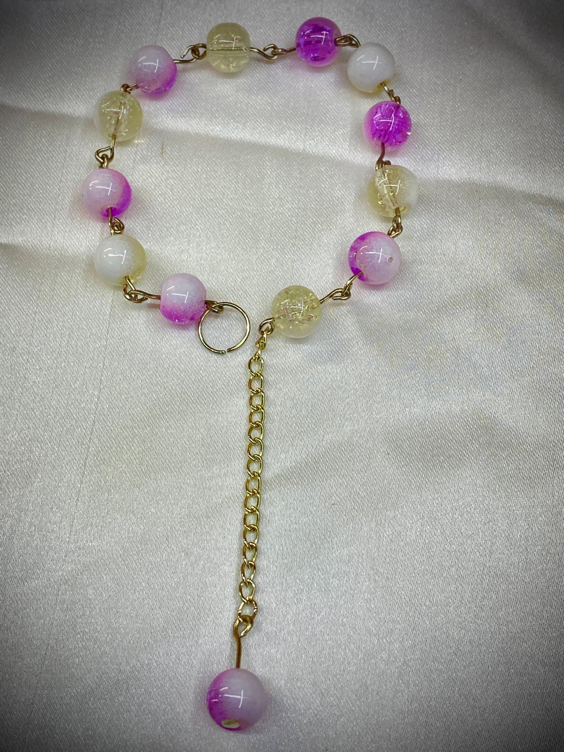 Necklace with pink and yellow beads on a white fabric background