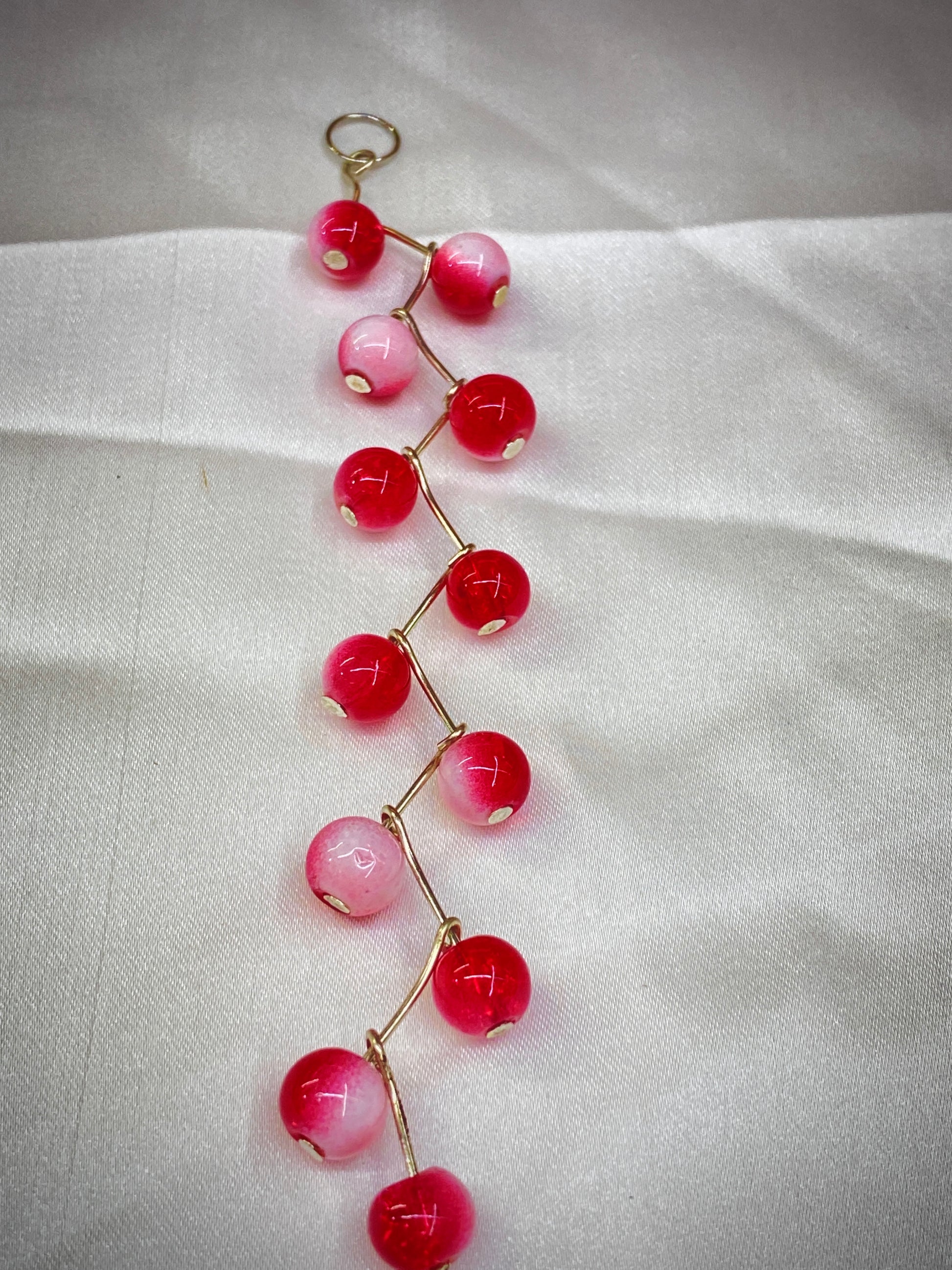 Bracelet with red and pink beads on a white fabric background