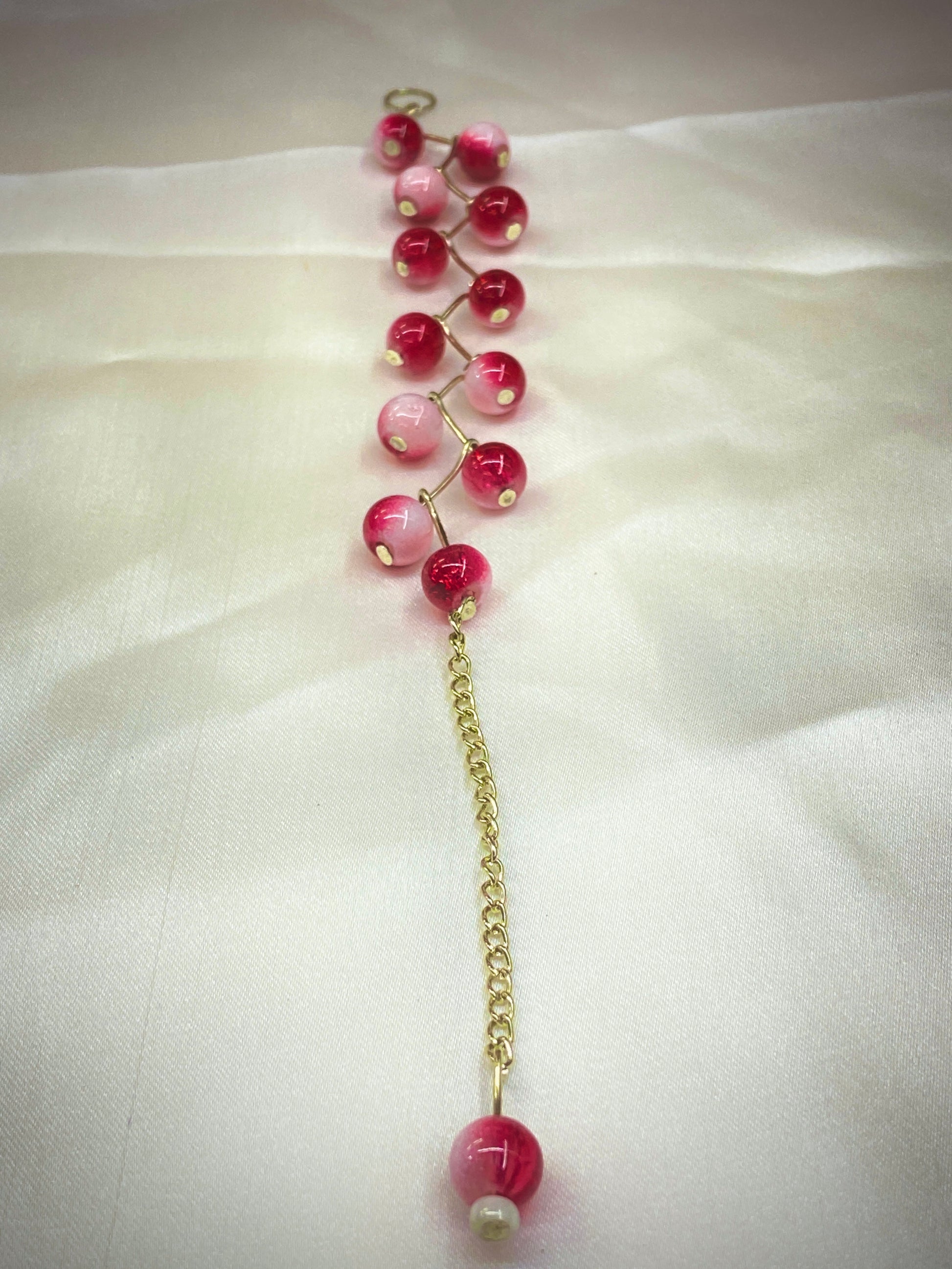 Necklace with pink and red beads on a white fabric background