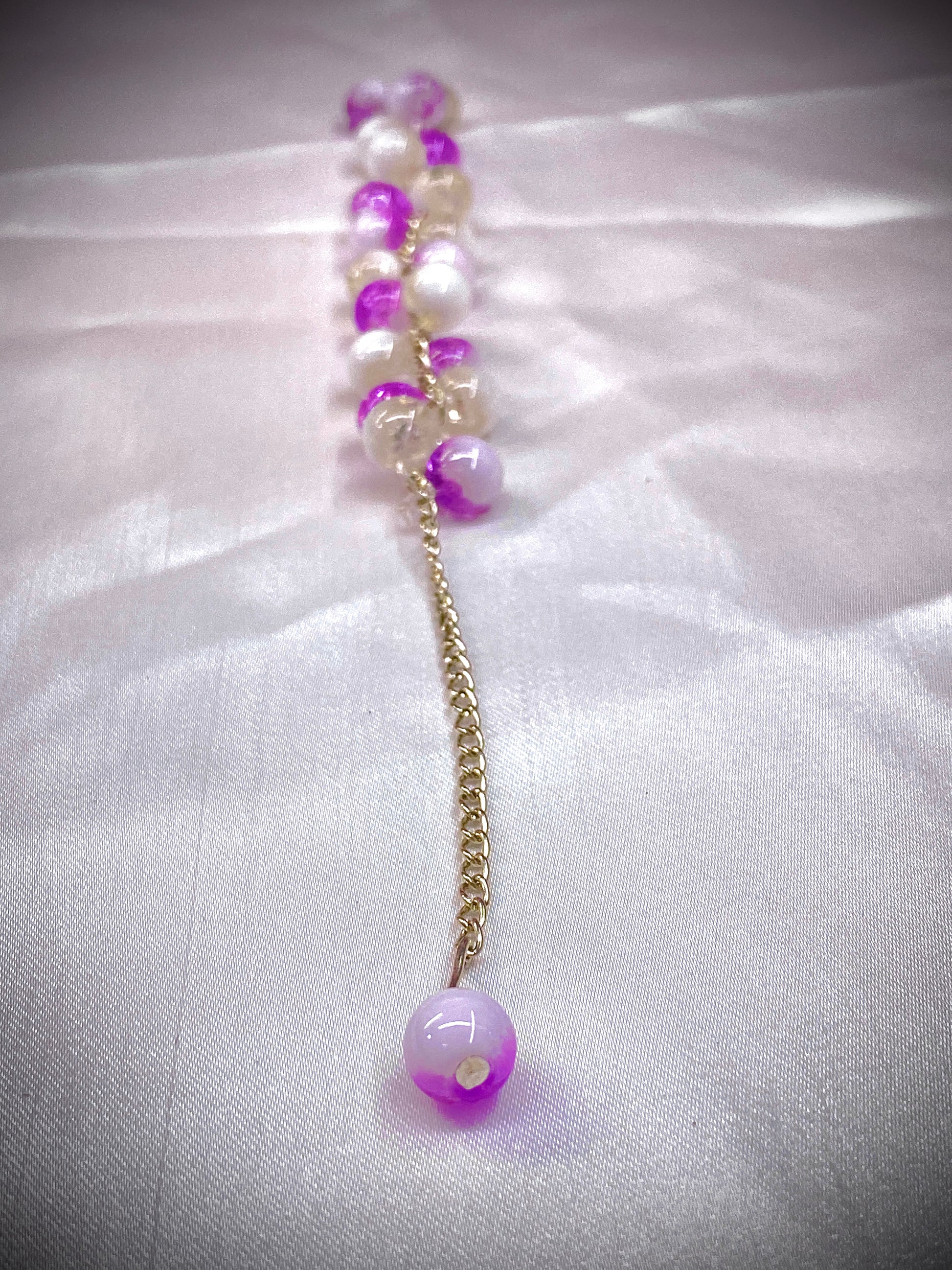Beaded necklace with purple and white beads on a white fabric background