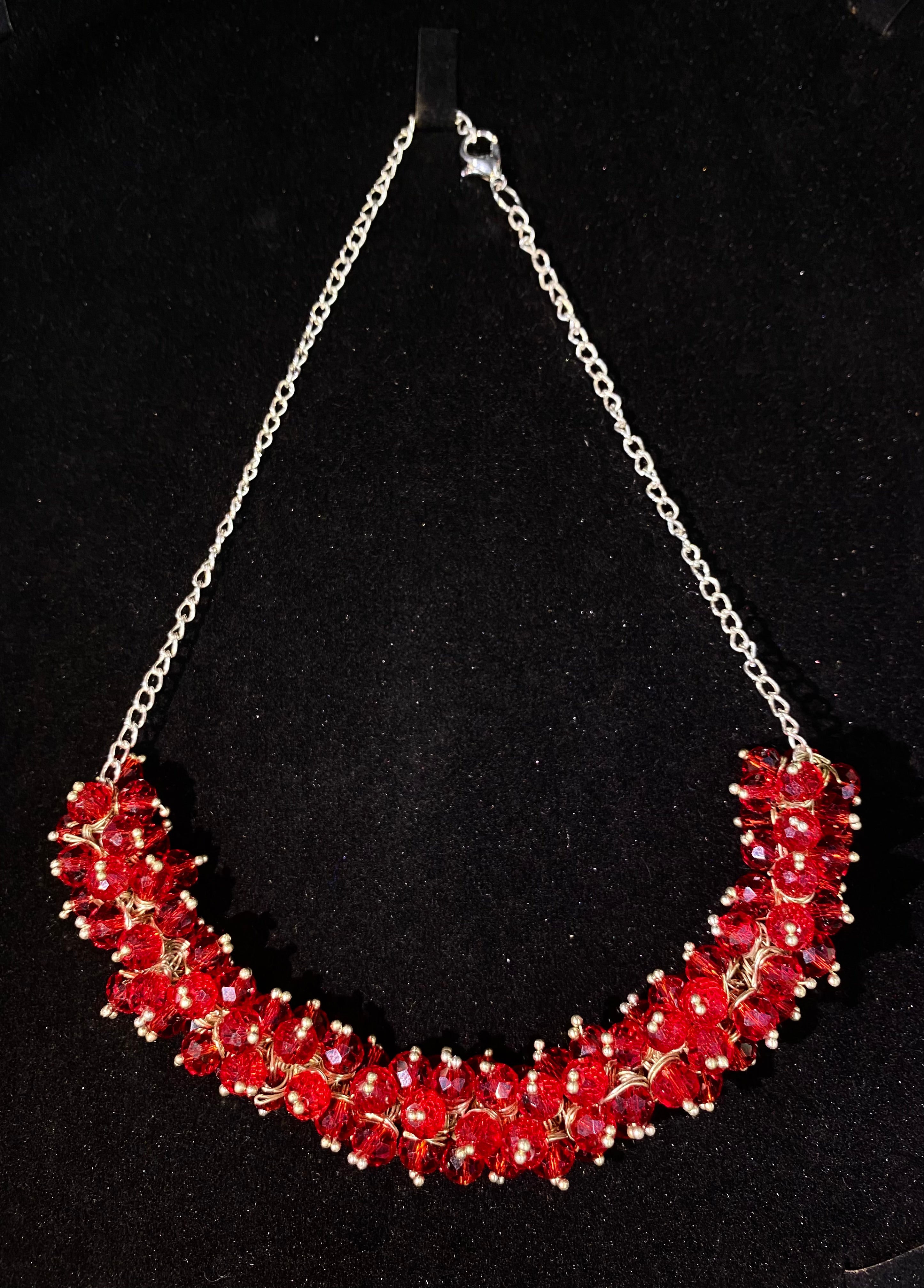 Red beaded necklace with a silver chain on a black background