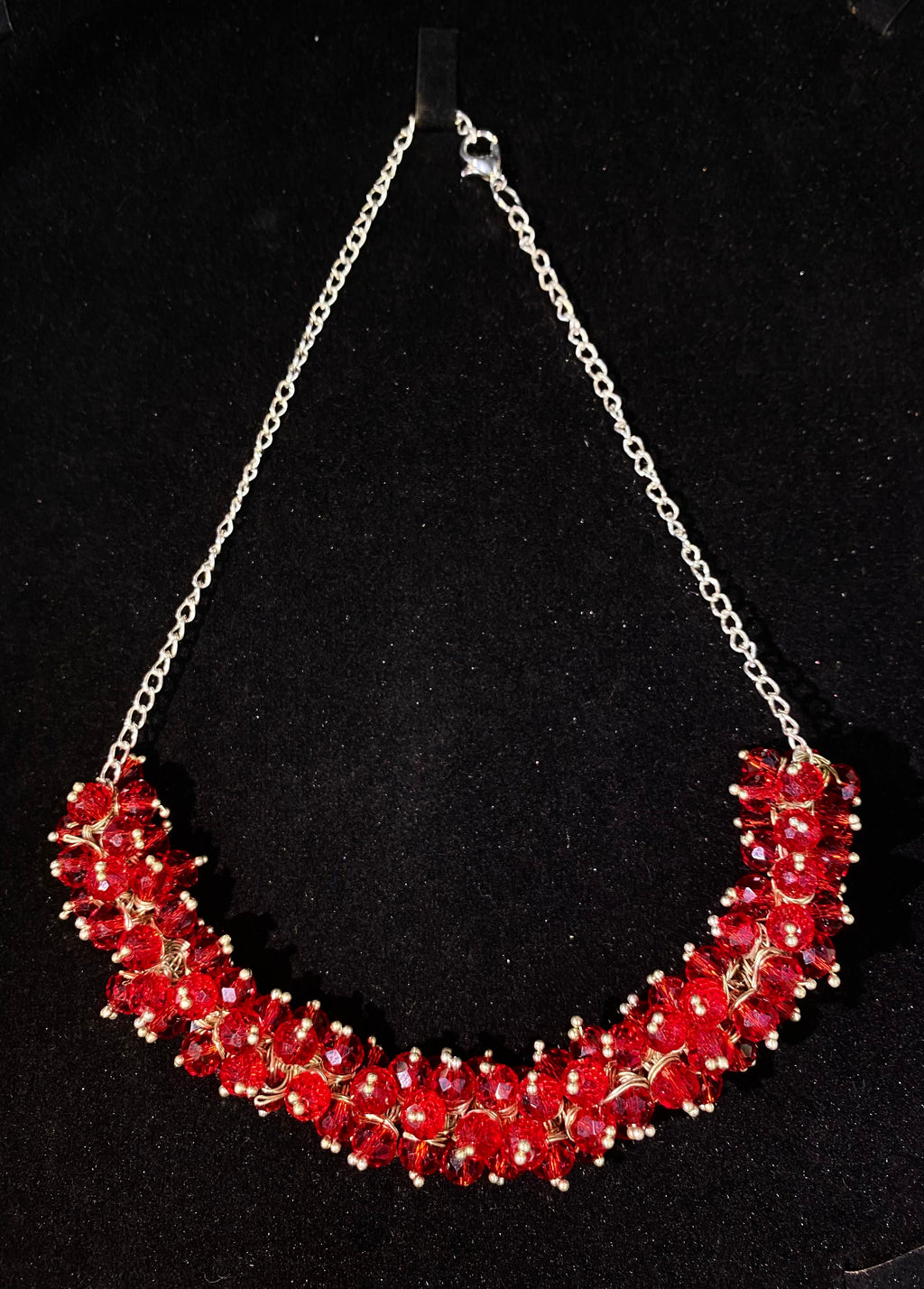 Red beaded necklace with a silver chain on a black background