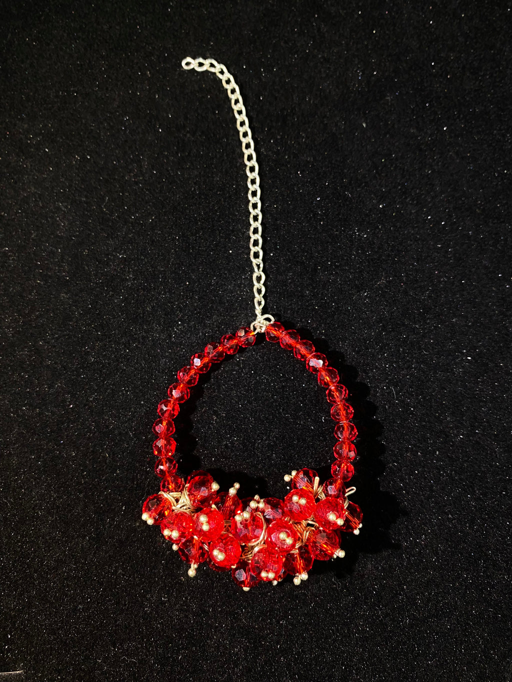 Red beaded circular ornament on a black background