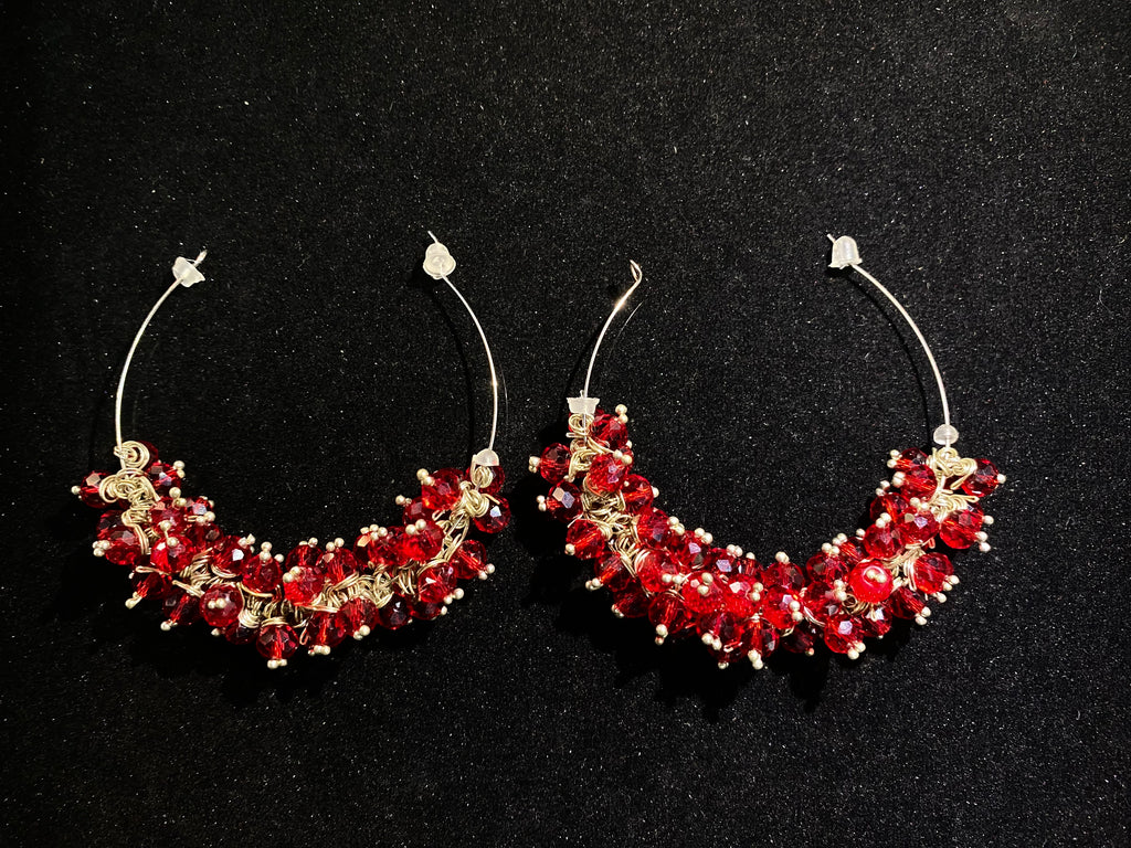 Pair of red and gold earrings on a black background