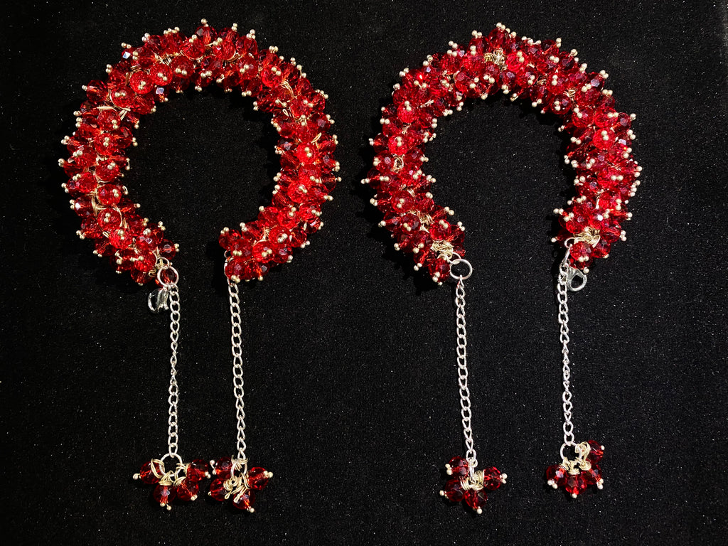 Pair of red beaded headbands with chain pendants on a black background