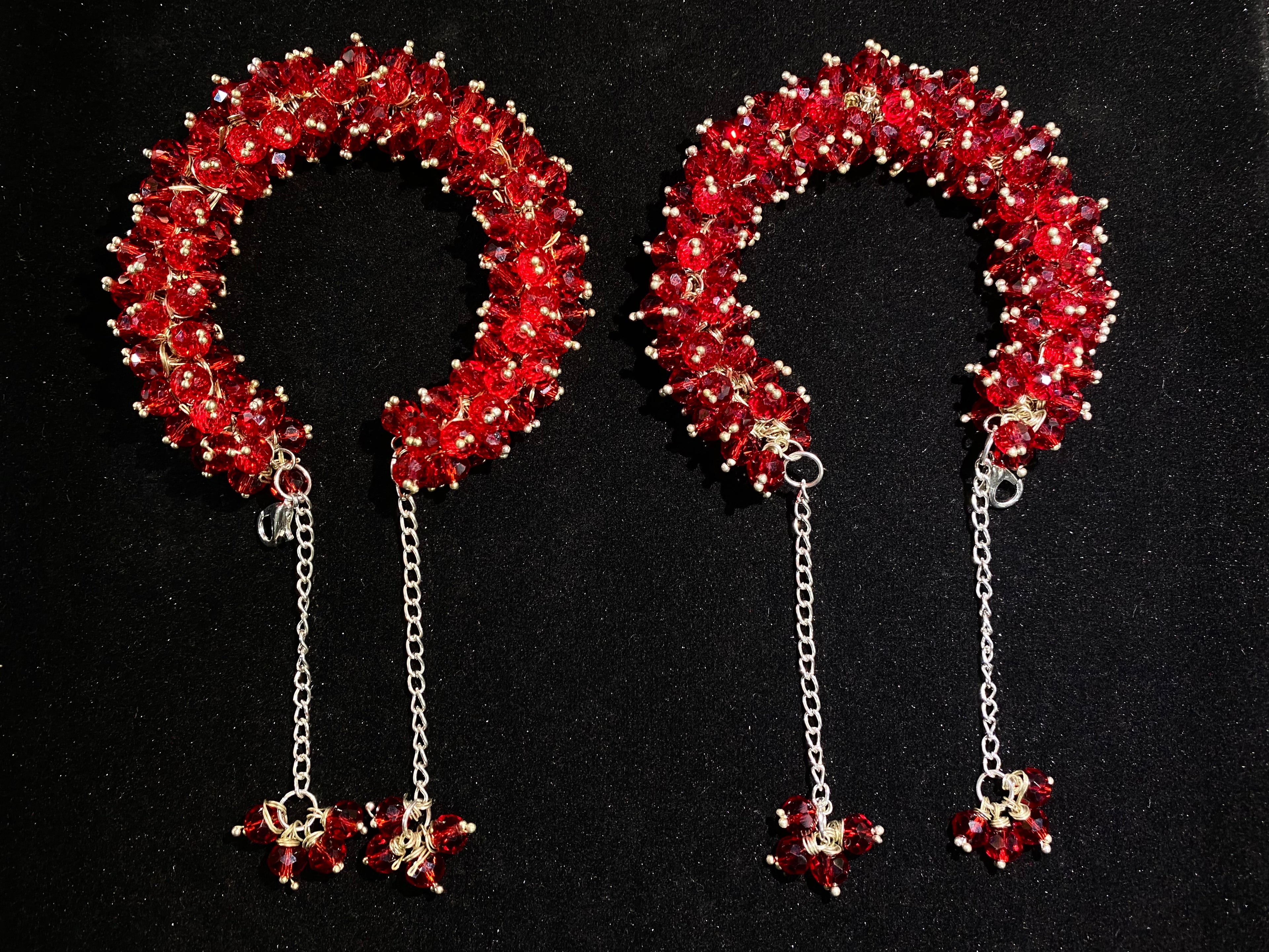 Pair of red beaded headbands with chain pendants on a black background