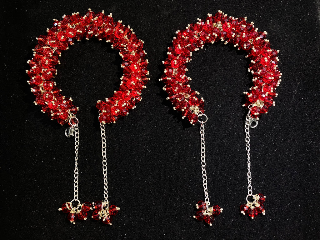 Pair of red beaded headbands with chain pendants on a black background