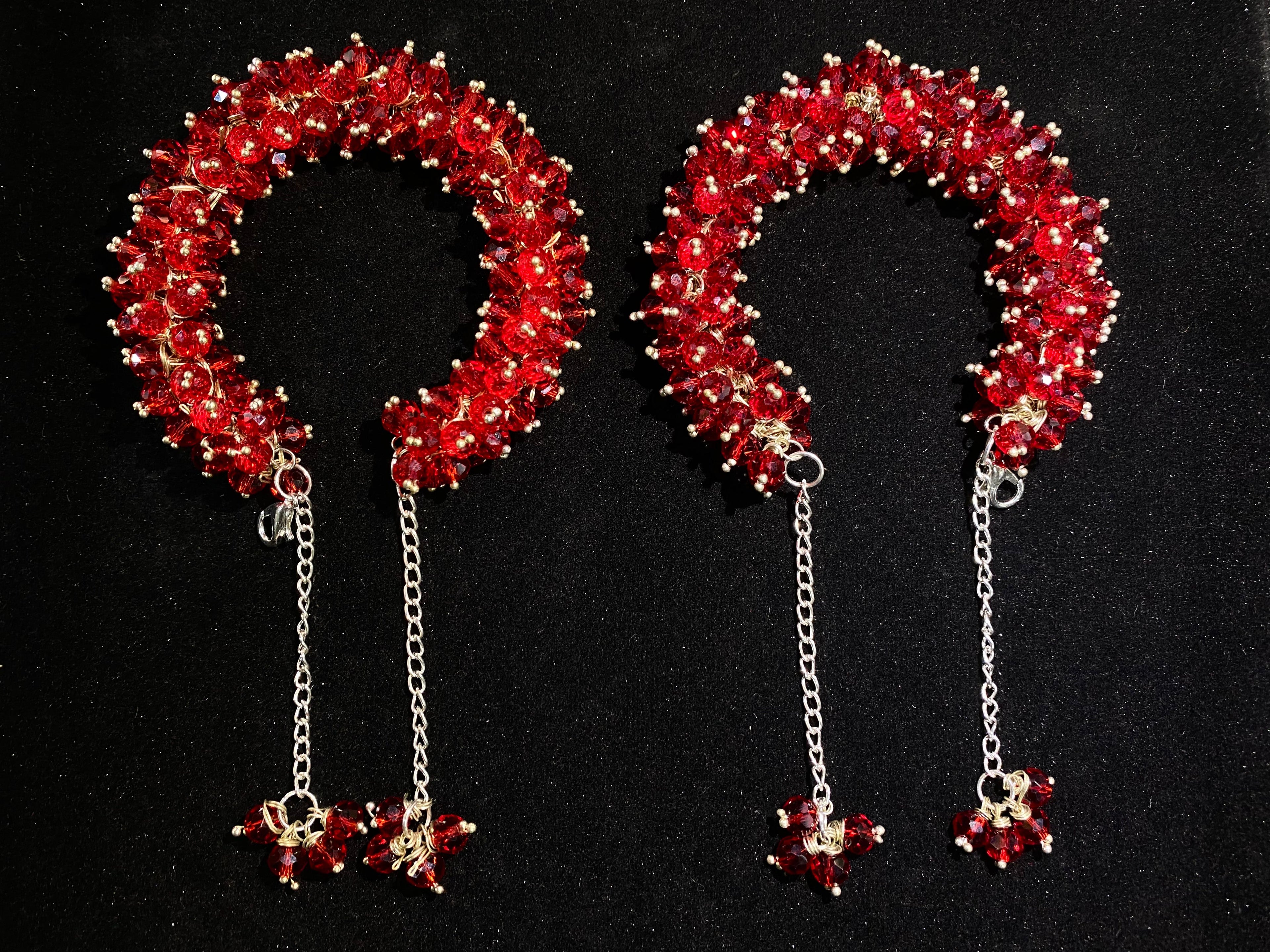 Pair of red beaded headbands with chain pendants on a black background