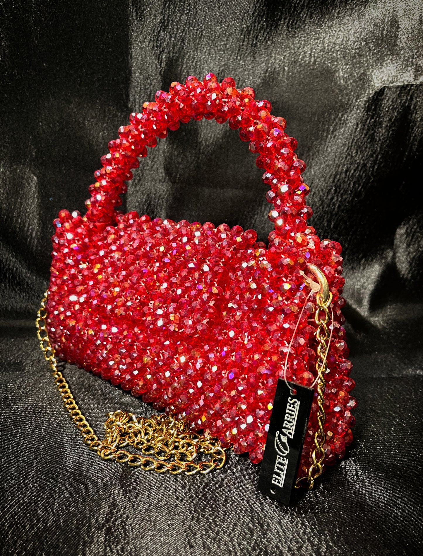 A dazzling red handbag with small glass pieces, radiating a luxurious shine.
