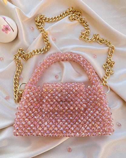 Pink beaded handbag with gold chain on a soft pink background
